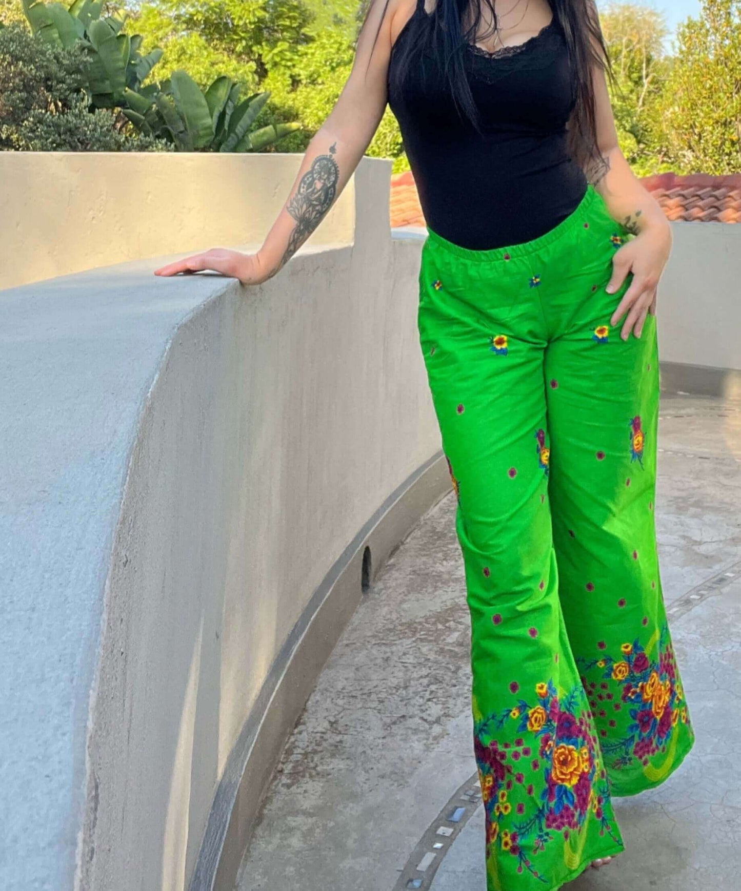 Front of pants, bright green background, small bright colorful flowers sprayed randomly, with large bold floral hem border.