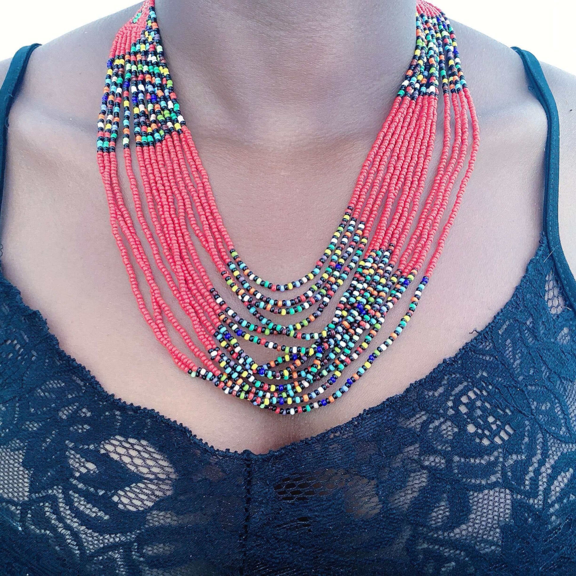 Detail view of thirteen strand zulu beaded necklace, in bands of red, alternating with darker multi color beads.