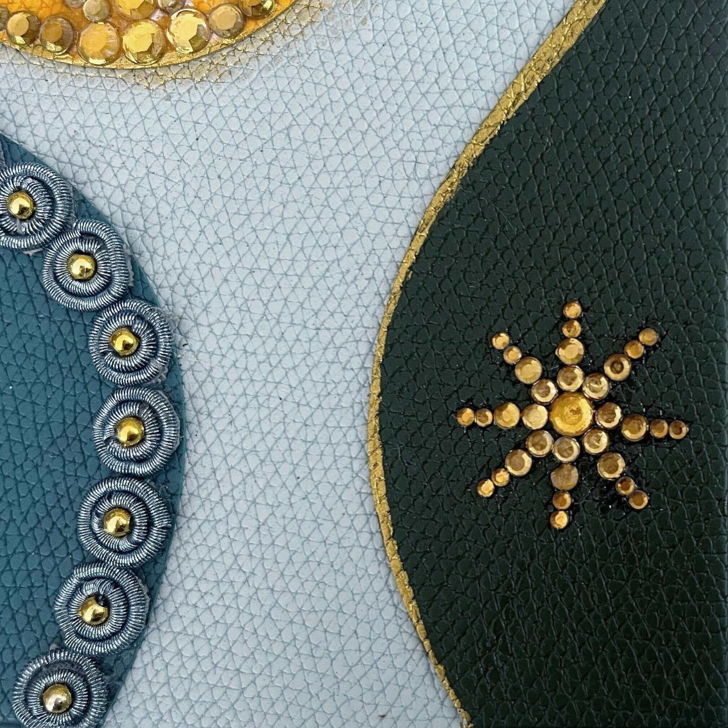 Detail view of journal showing the black blotch with gold crystals, and the blue one with blue beaded charms.
