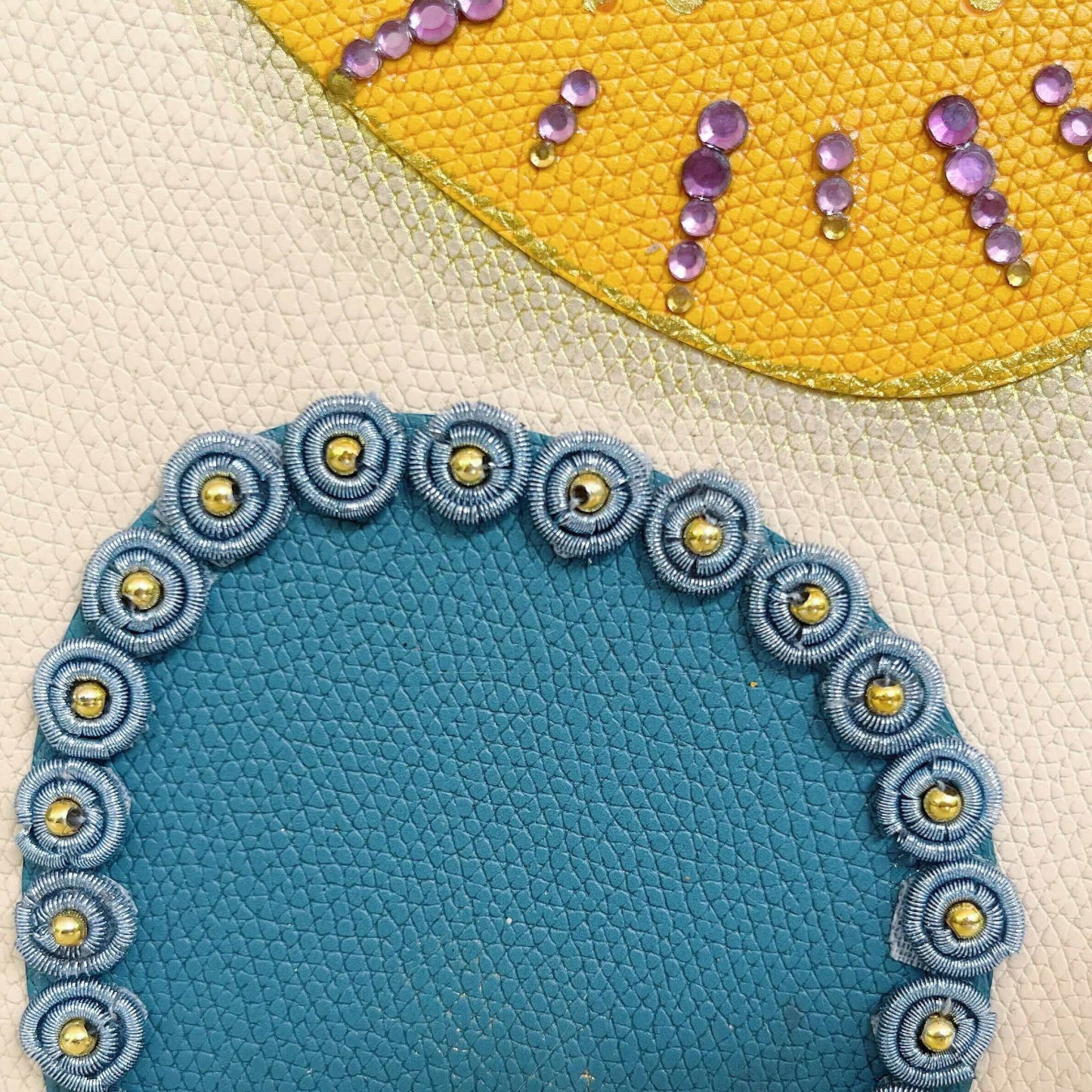 Detail view of journal showing the yellow blotch with gold crystals, and the blue one with blue beaded charms.