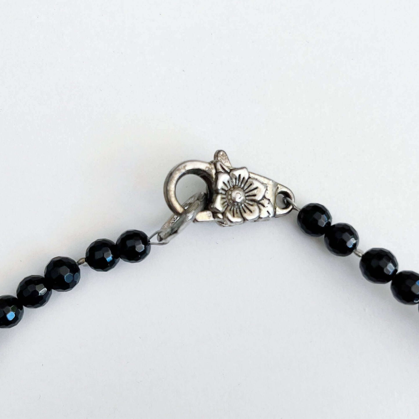 Detail view of the faceted beads, and silver finish floral clasp.