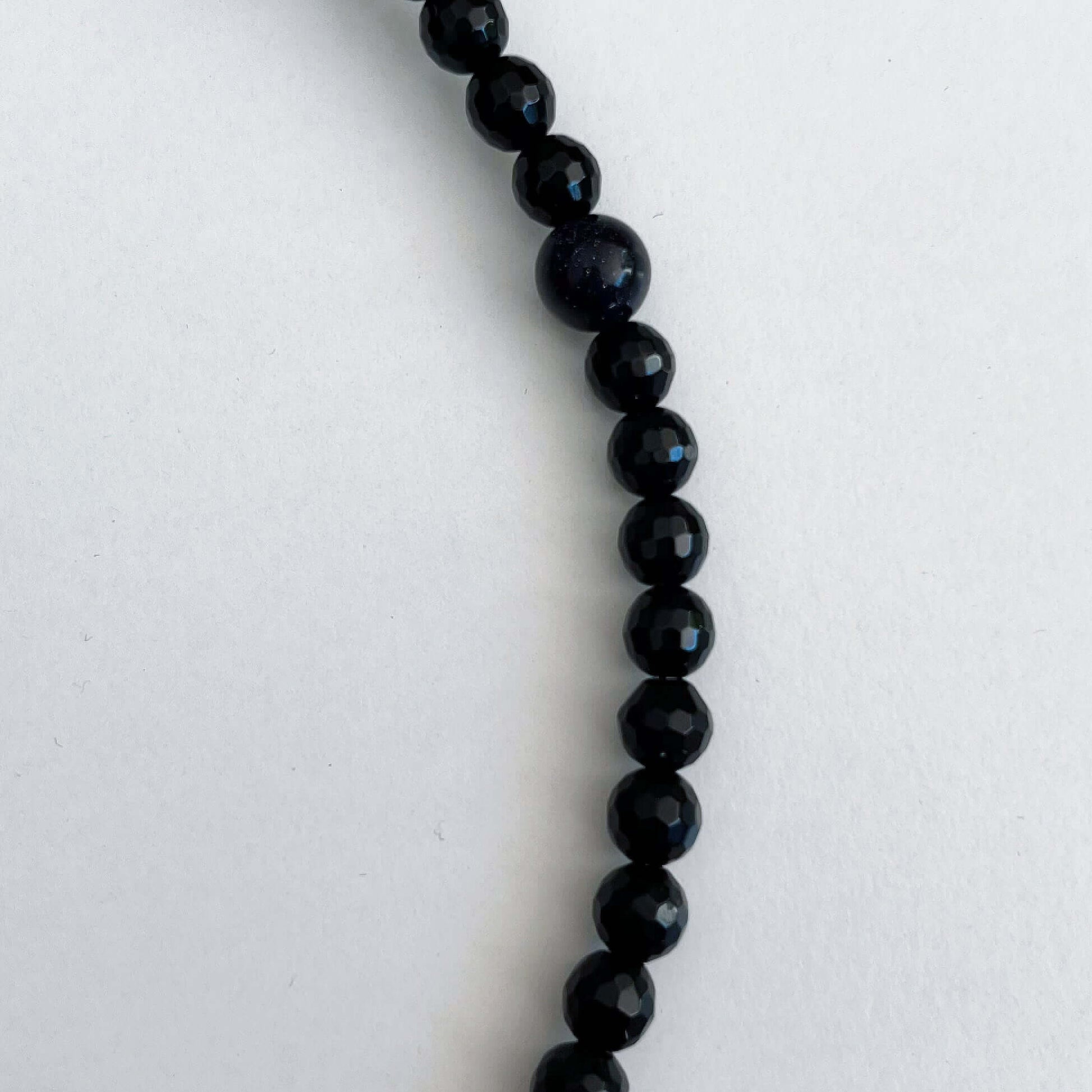 Detail view of the Obsidian beads, smooth and faceted. A single starstone bead has been inserted for good luck.