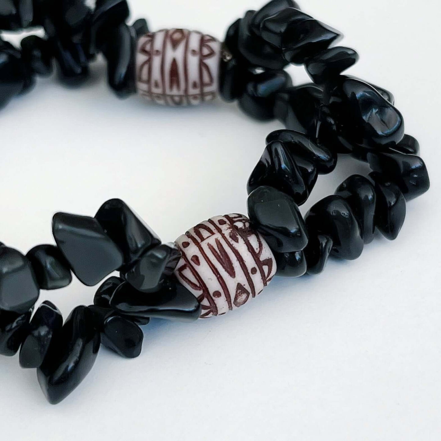 Detail view of double-strand tumbled chip bracelet, with a white and maroon African style bead positioned in 3 places.