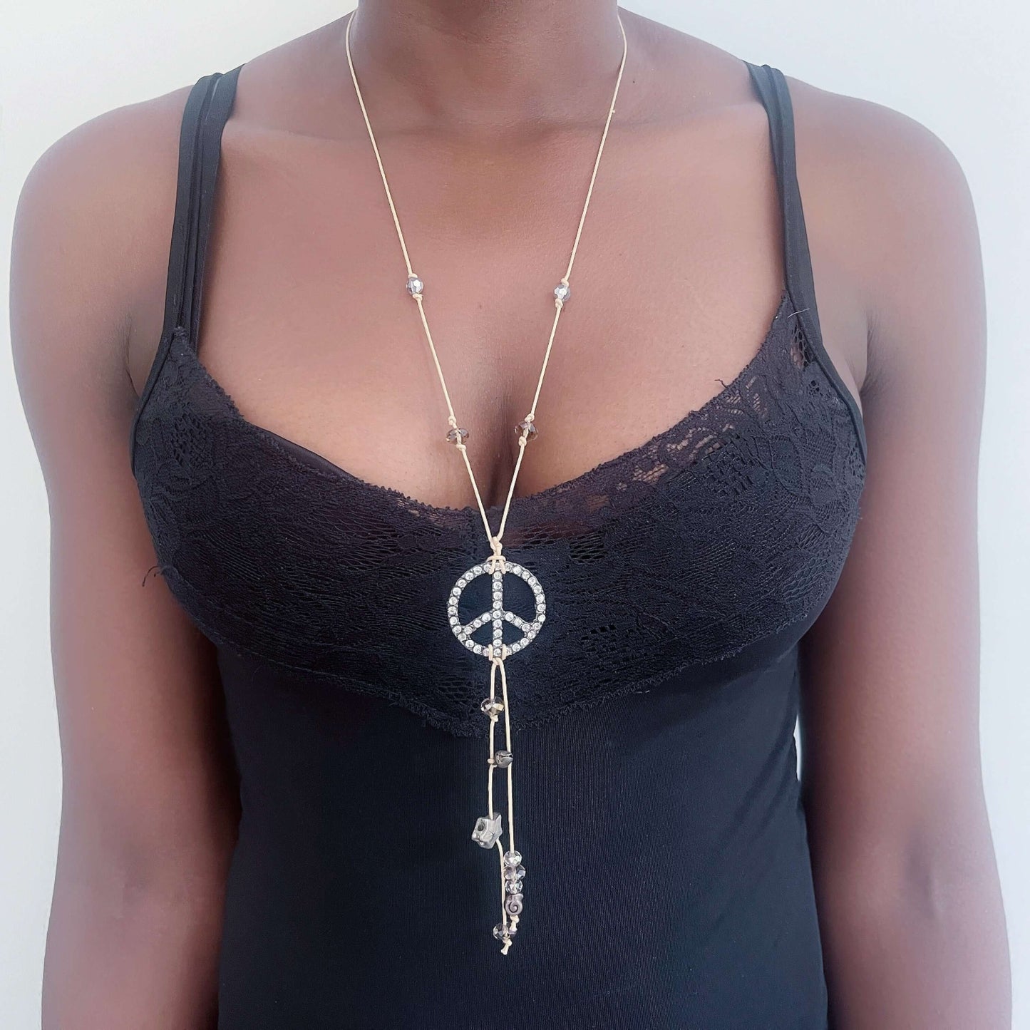 Adjustable beige thong necklace with knotted crystals, and diamante encrusted peace sign.