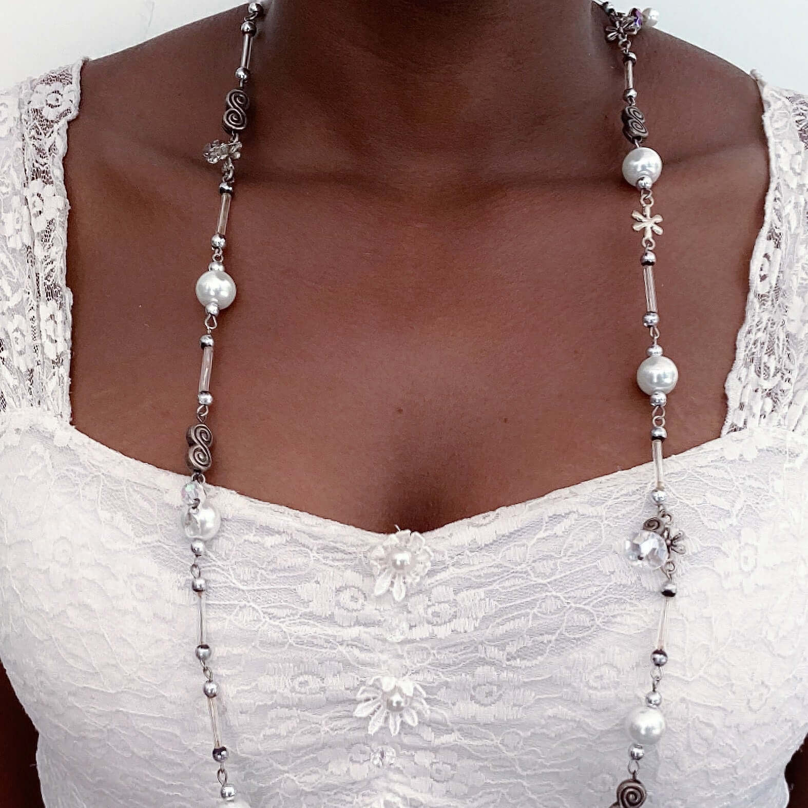 Detail view of necklace beaded with costume pearls, crystals, beads and charms, all shades of clear and white.