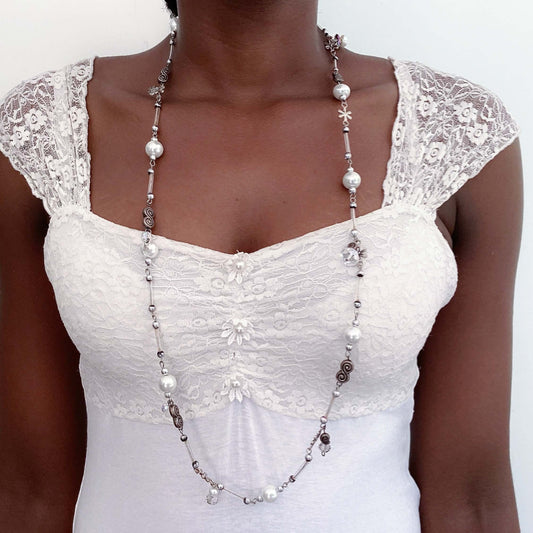 Front view of necklace beaded with costume pearls, crystals, beads and charms, all shades of clear and white.