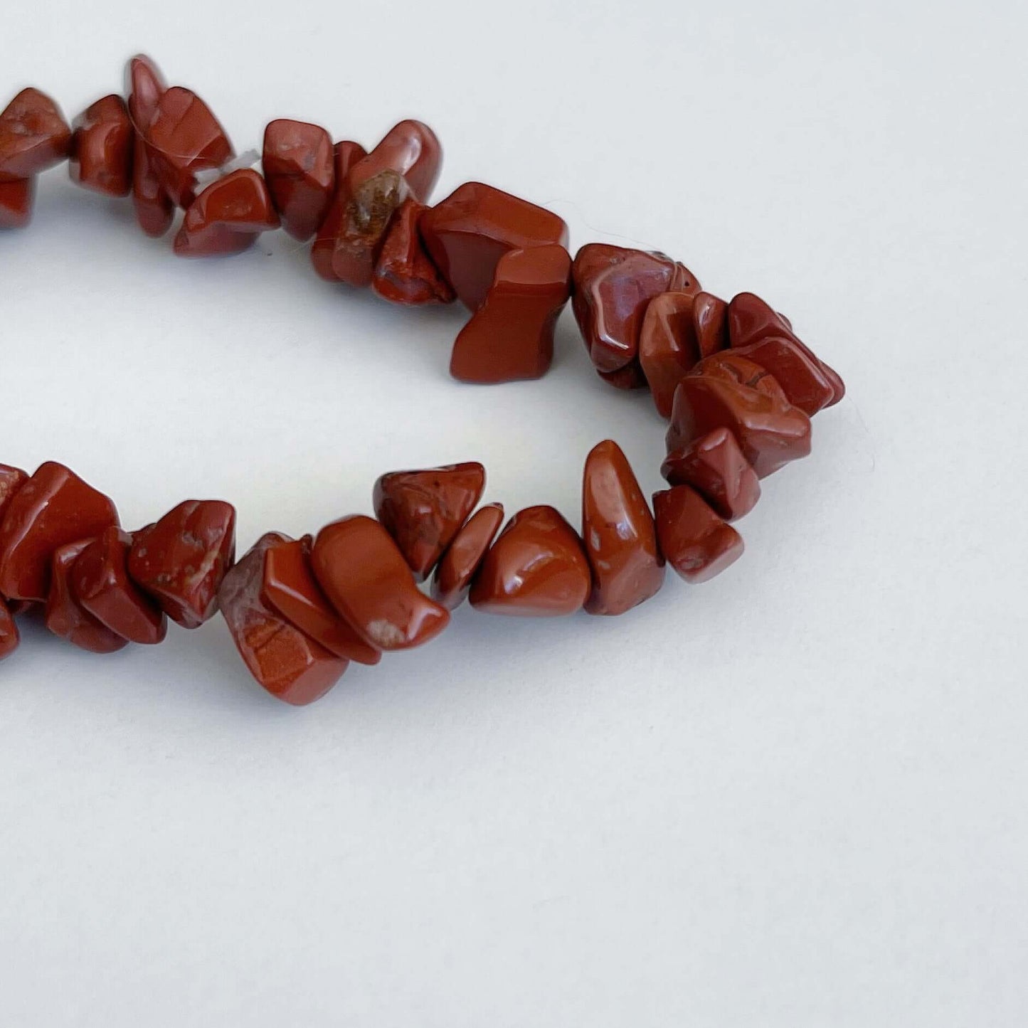 Detail view of the tumbled semi-precious stones, vibrant shades deep rust/brown red.