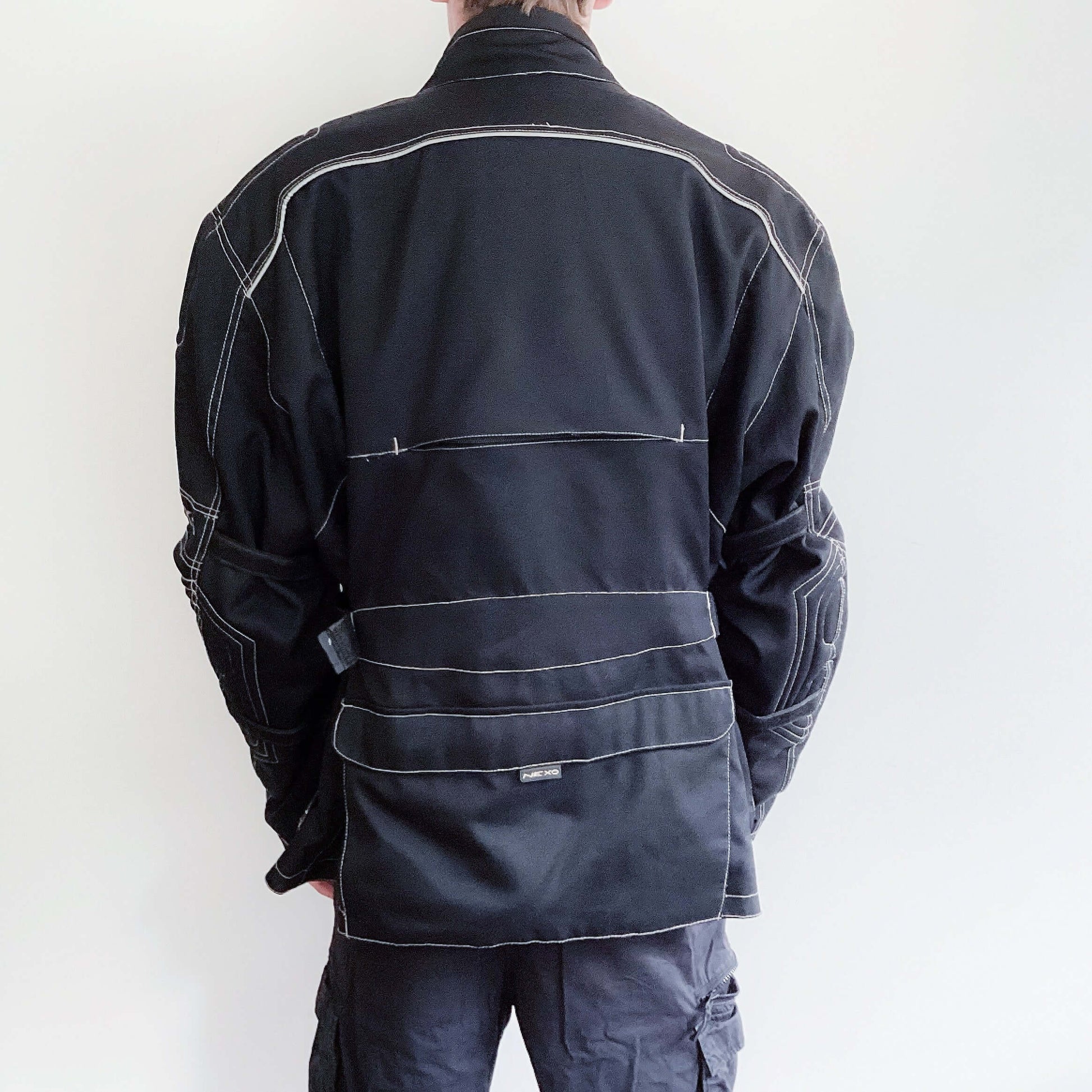 Back view of well padded zipper jacket, black all over with white stitching on all edges, hip length, multiple pockets.