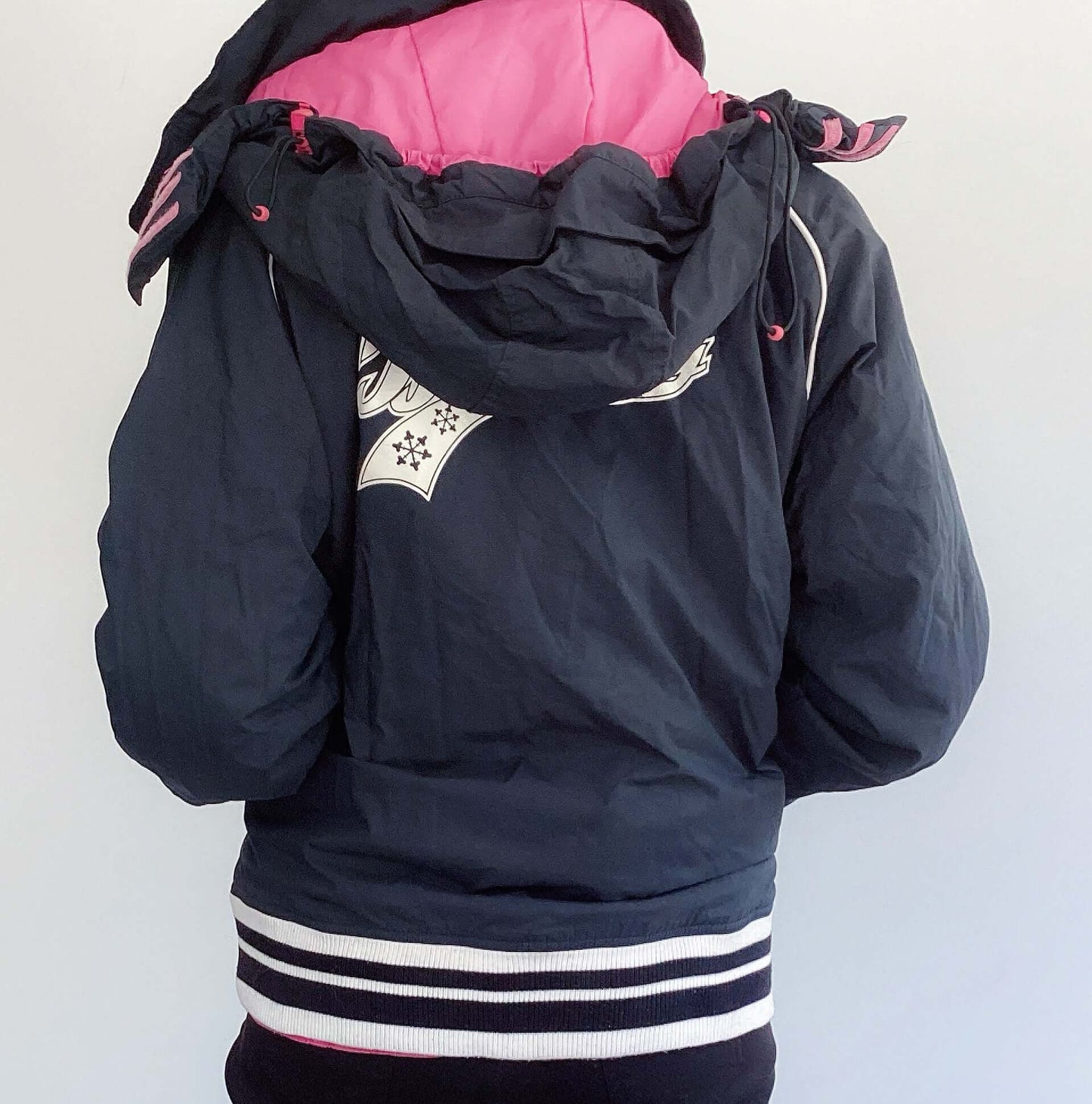 Back of black jacket with pink lining, black and white striped cuff and hem ribbing, white billabong print on the back.