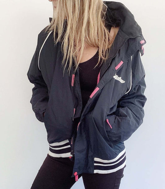 Front of black jacket with pink lining, black and white striped cuff and hem ribbing, white billabong print on the back.