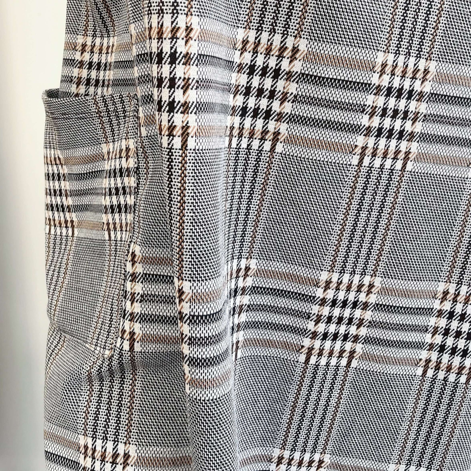 Detail view of tartan dungaree dress fabric, beautiful weave of greys, browns an black.