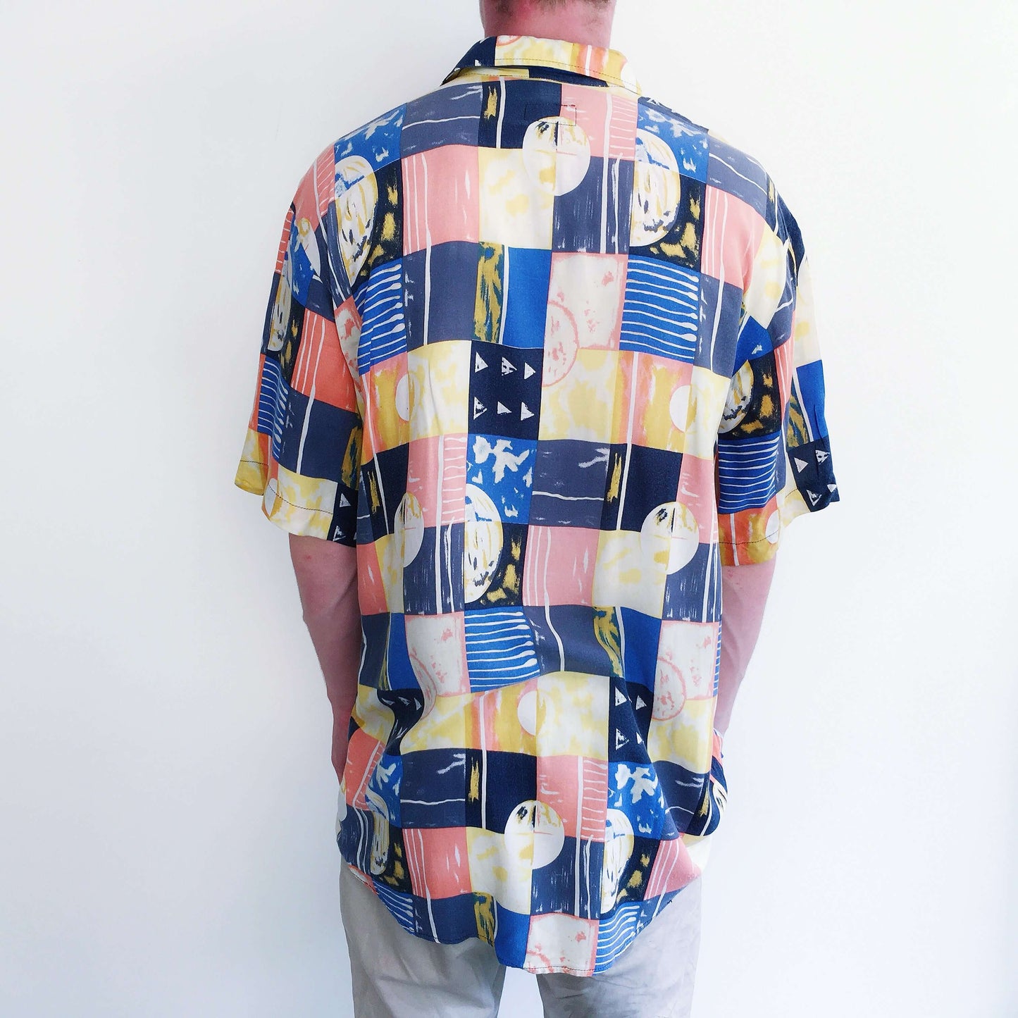 Back view of large cubist checked shirt, of orange, blue, and white, button down, and drop shoulder short sleeved.