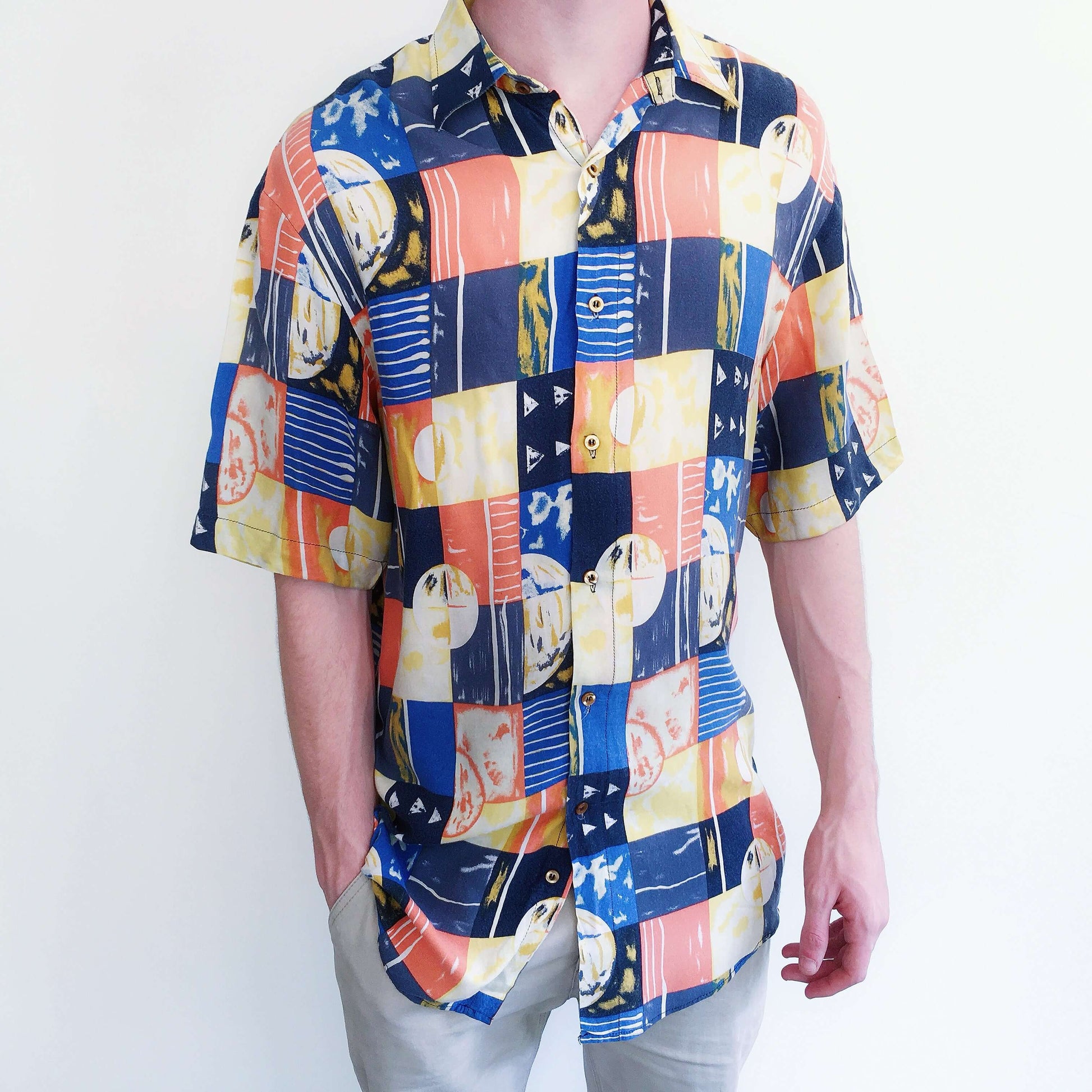 Front view of large cubist checked shirt, of orange, blue, and white, button down, and drop shoulder short sleeved.