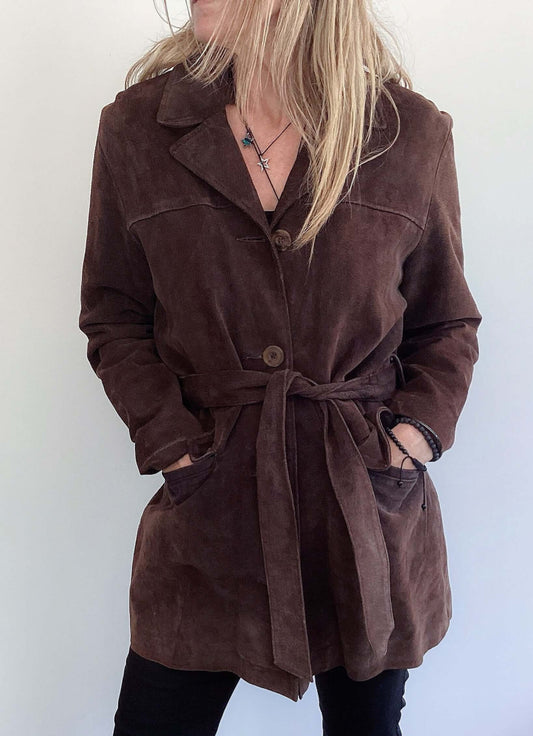 Front view of chocolate brown button up suede jacket, mid thigh length, with belt and front pockets.