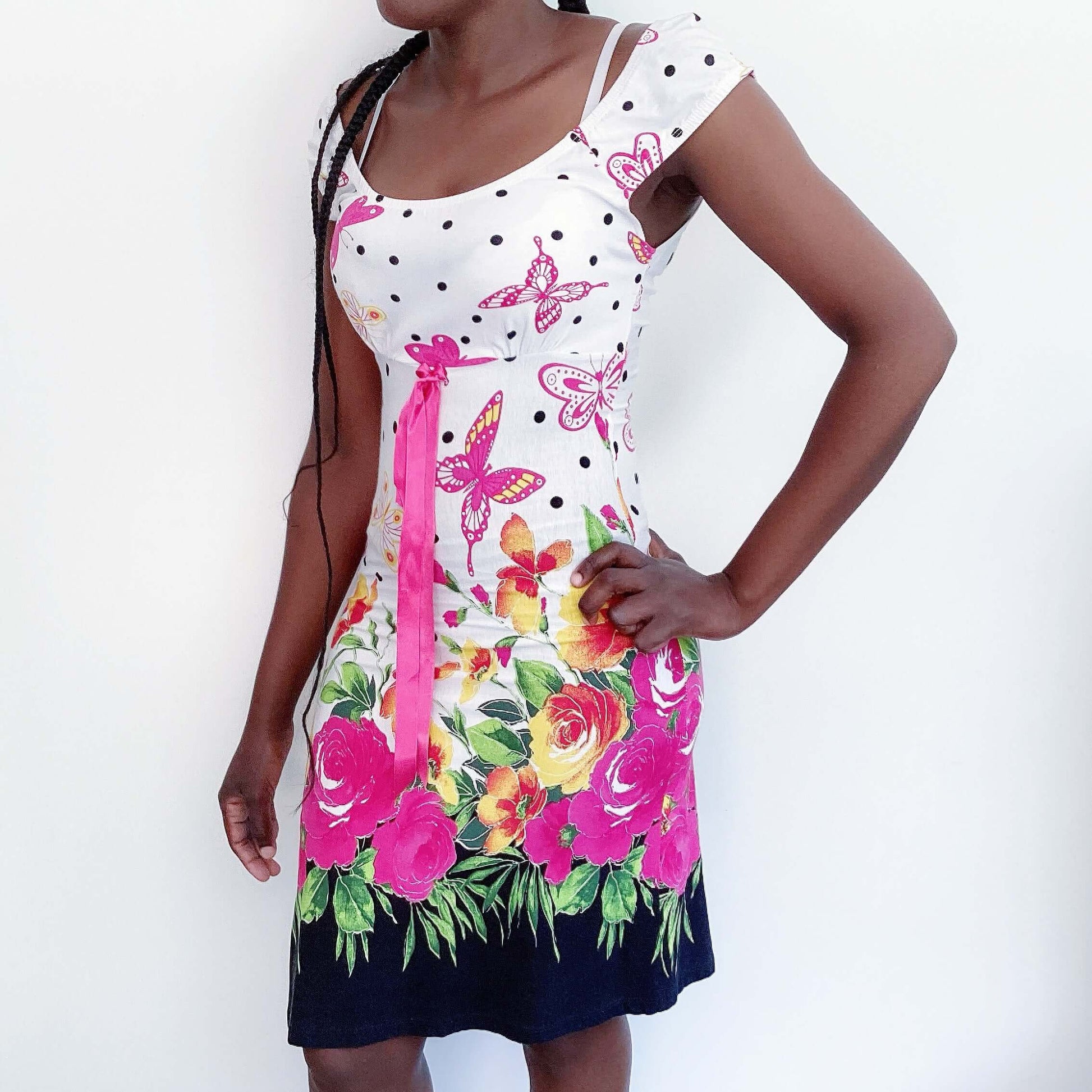 Front view of white cotton mini dress with pink butterflies and roses, pink ribbon in the center under bust, and black dots.