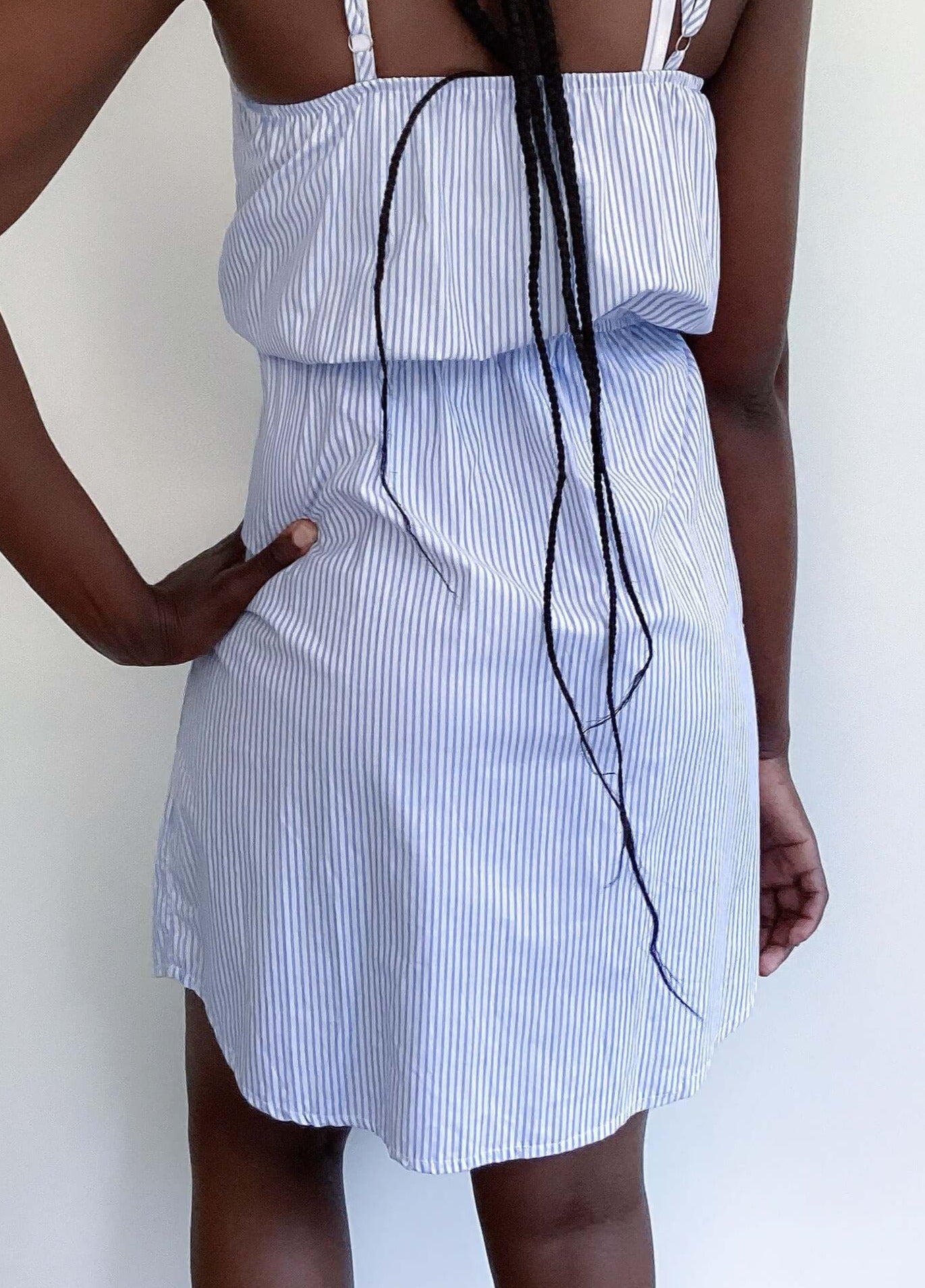 Pale blue and white striped v-neck dress, above knee, thin straps and elasticated waist, back view.