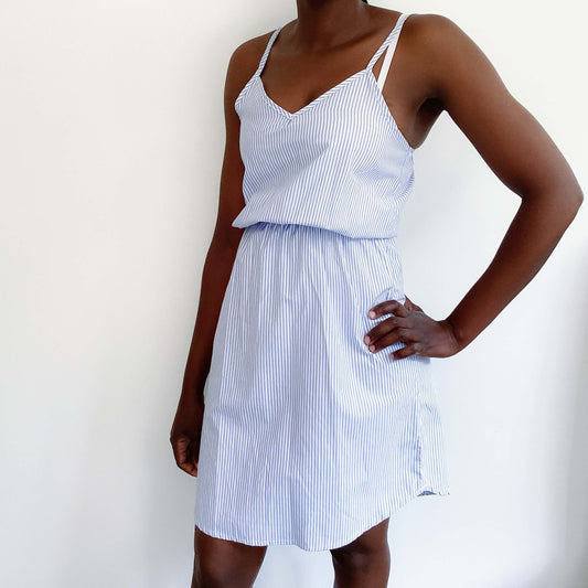 Pale blue and white striped v-neck dress, above knee, thin straps and elasticated waist, side view.