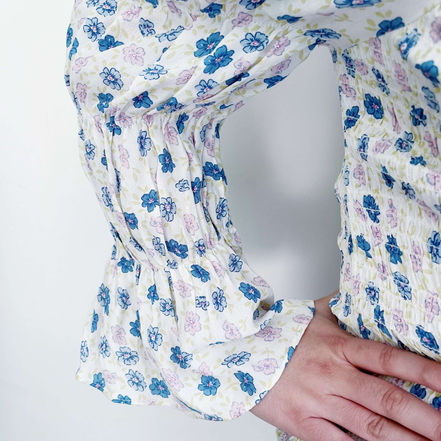 Detail view of the sleeve, white cotton, with delicate blue and pink flower print, and ruched at the wrist.