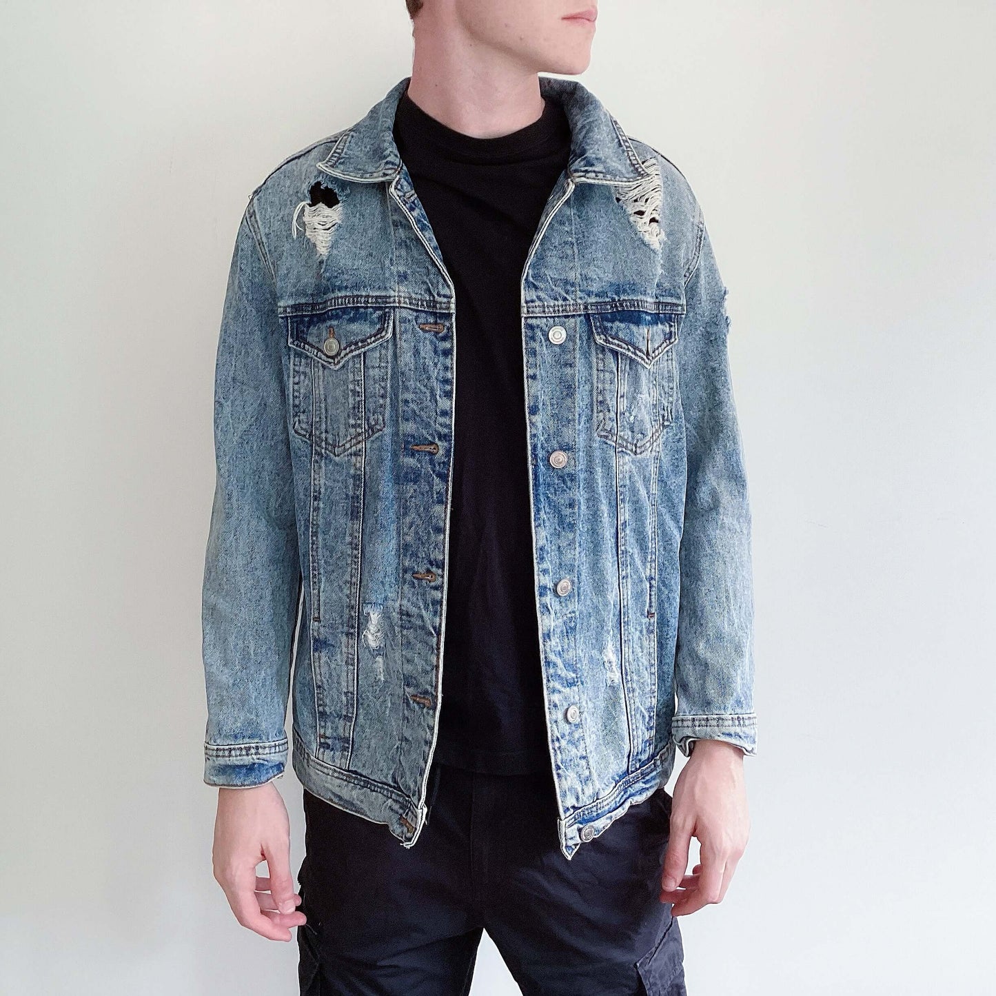 Blue snow-washed denim jacket with rips here and there