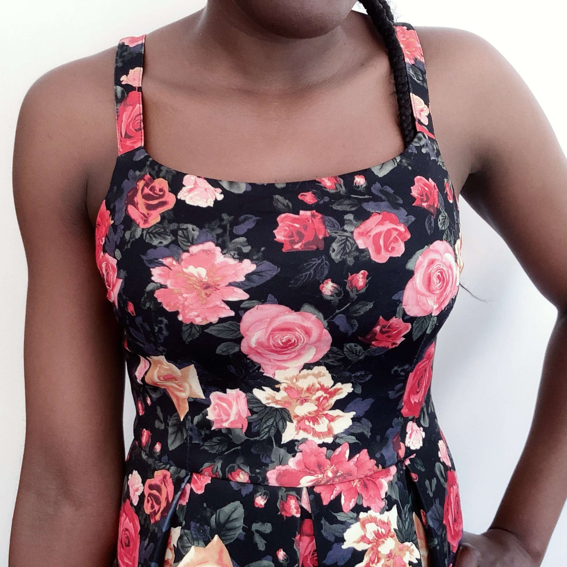 Detail view zipper black mini dress, with red and orange roses all over, tight bodice, flared skirt, medium width straps.