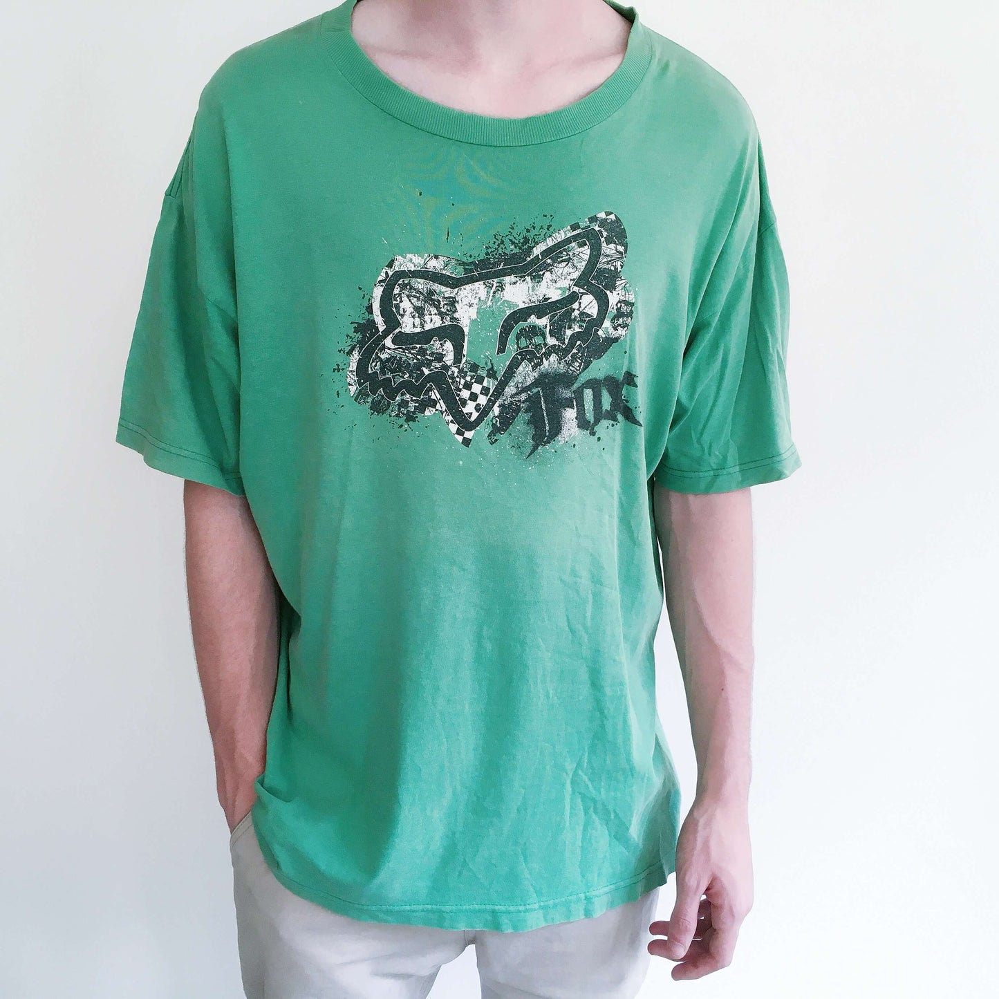 Front view of aqua green drop shoulder tshirt, with black printing of the fox logo on the chest.