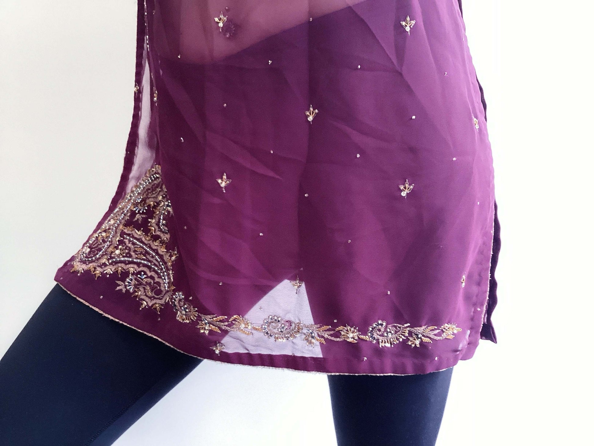 Front view detail of plum tunic, gold embroidery on the hem borders, side slits.