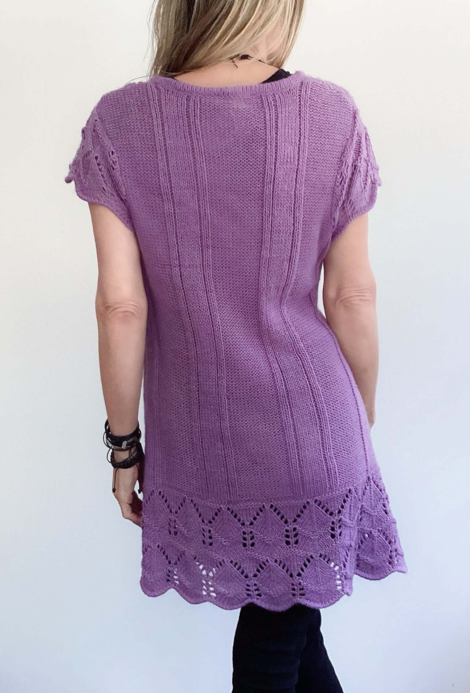 Back view of purple button up cardigan, celtic cable knit stitches, scalloped at the hem and sleeves, mid thigh length.