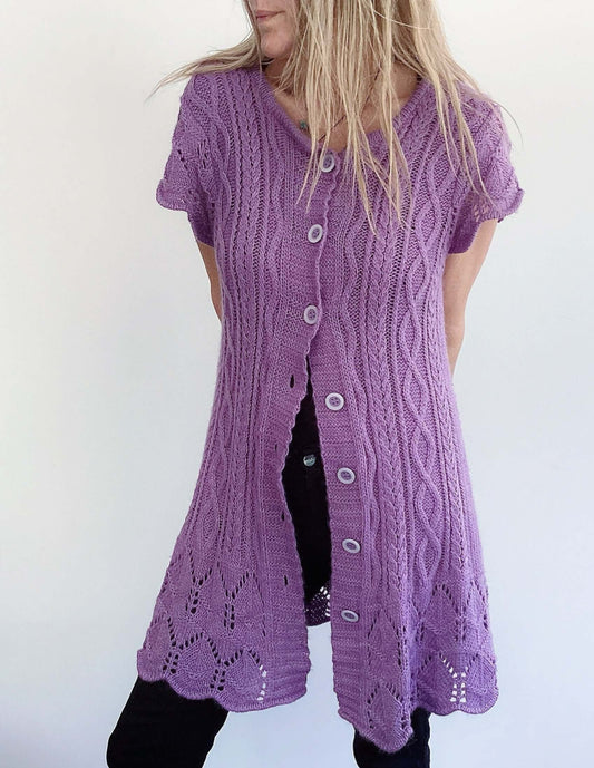 Front view of purple button up cardigan, celtic cable knit stitches, scalloped at the hem and sleeves, mid thigh length.