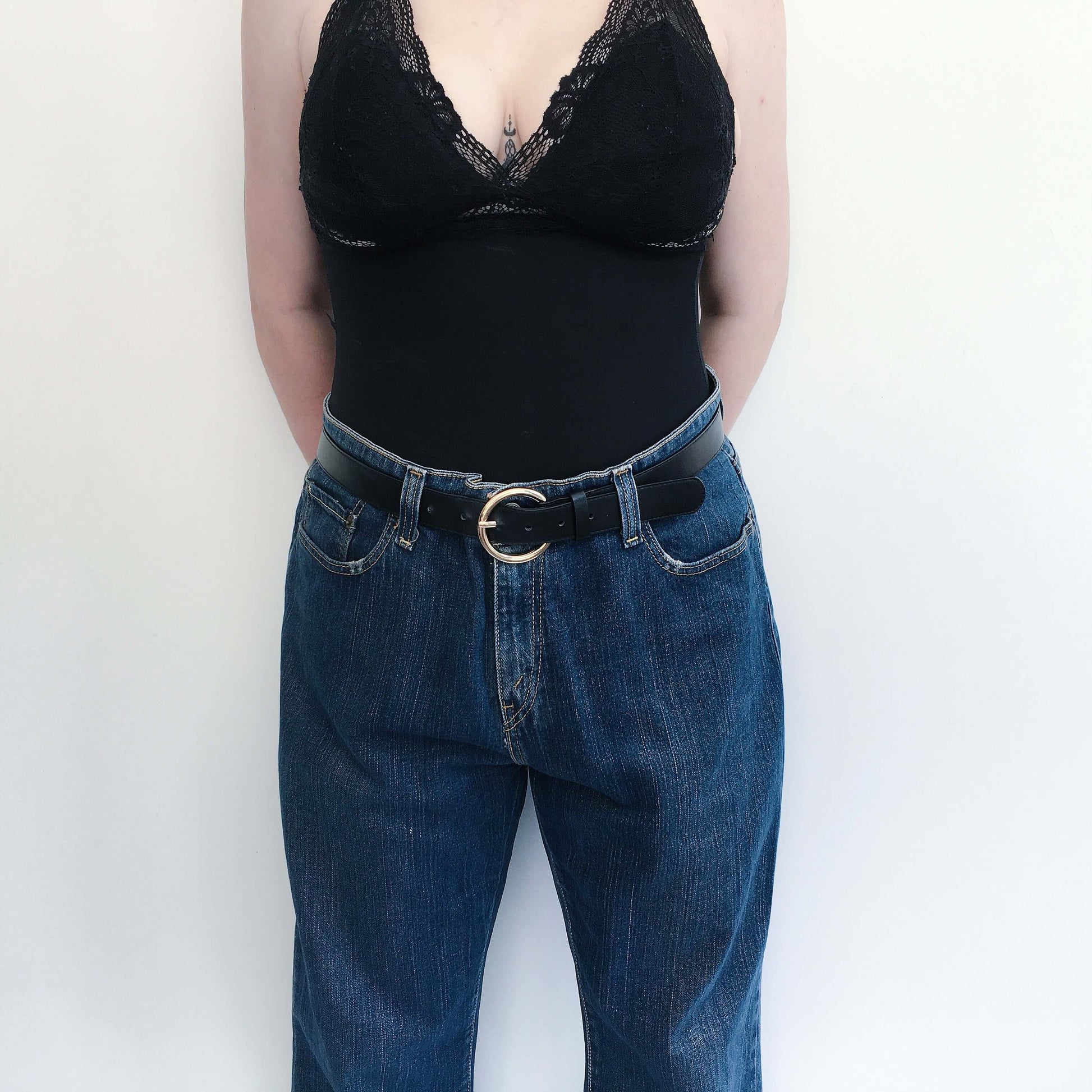 Front detail view of blue jeans belted at the waist with zip.