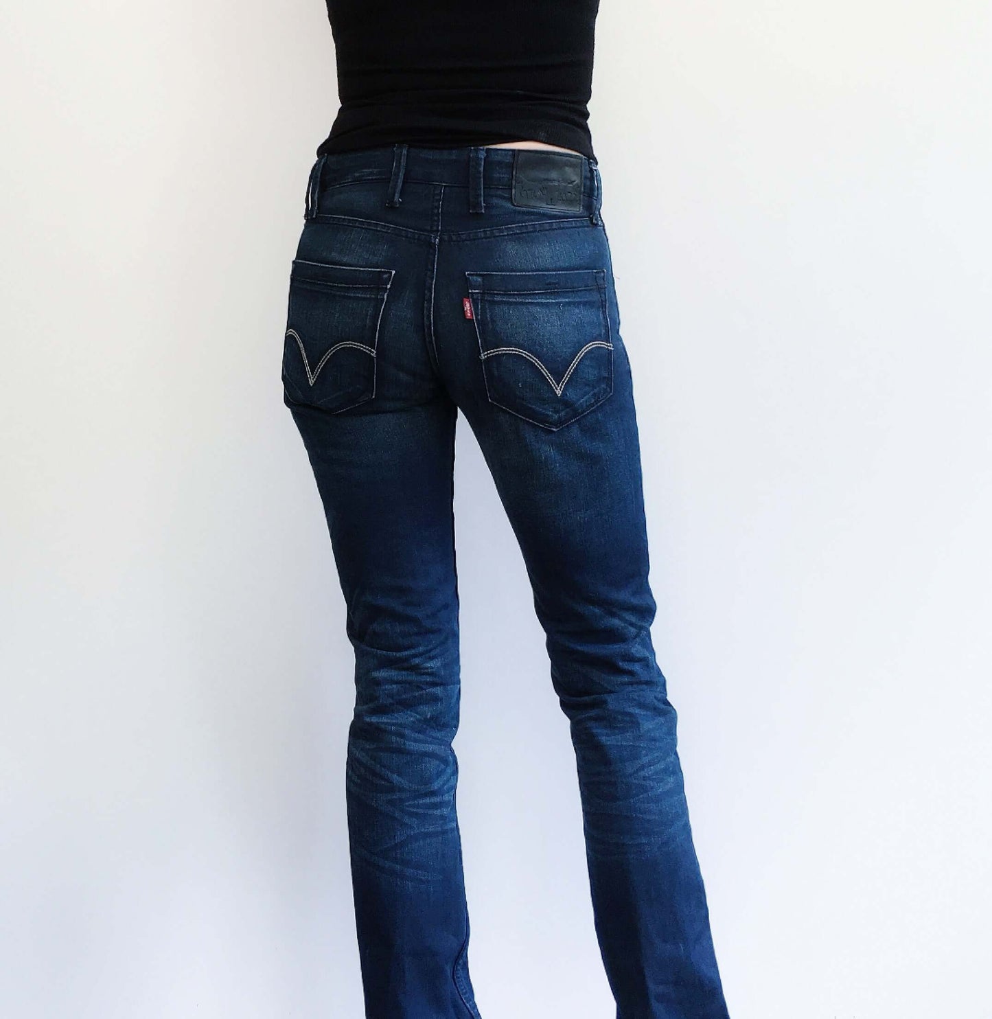 Back view of dark blue jeans, full length pic hands in pockets.