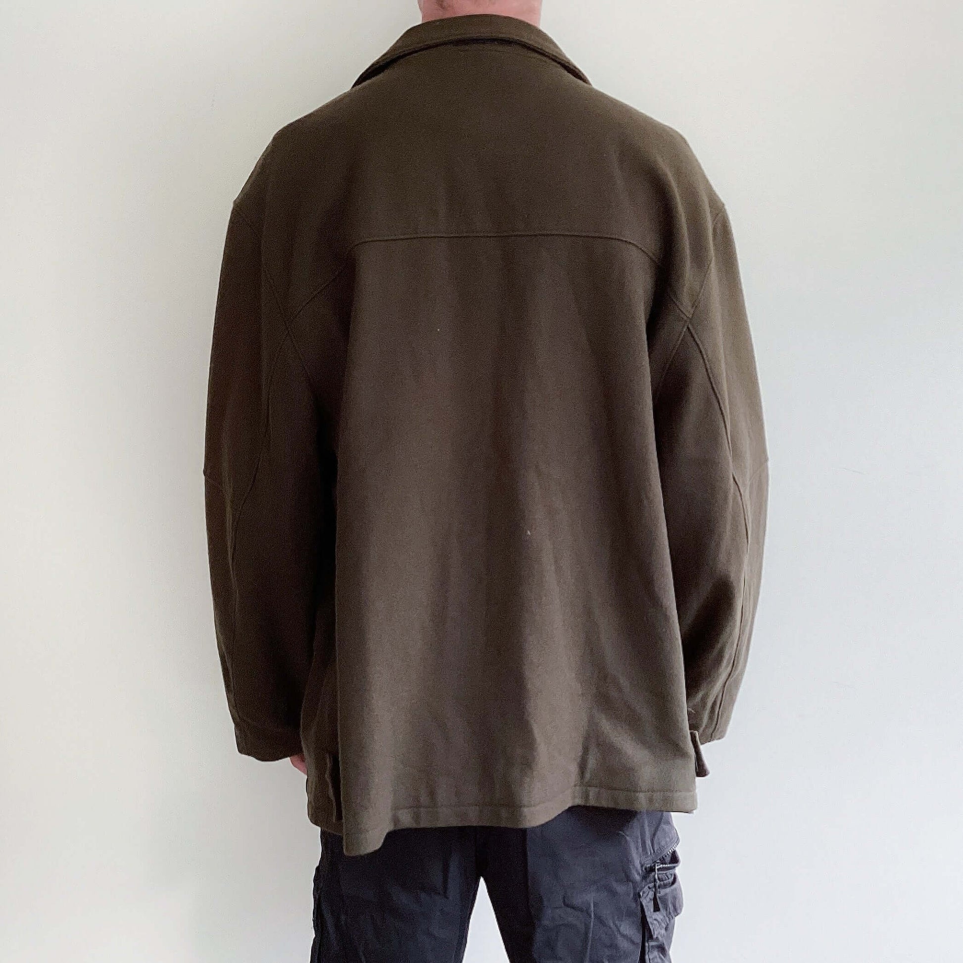 Back view of the jacket, deep brown/olive hue, zip and large stud closing mechanism.