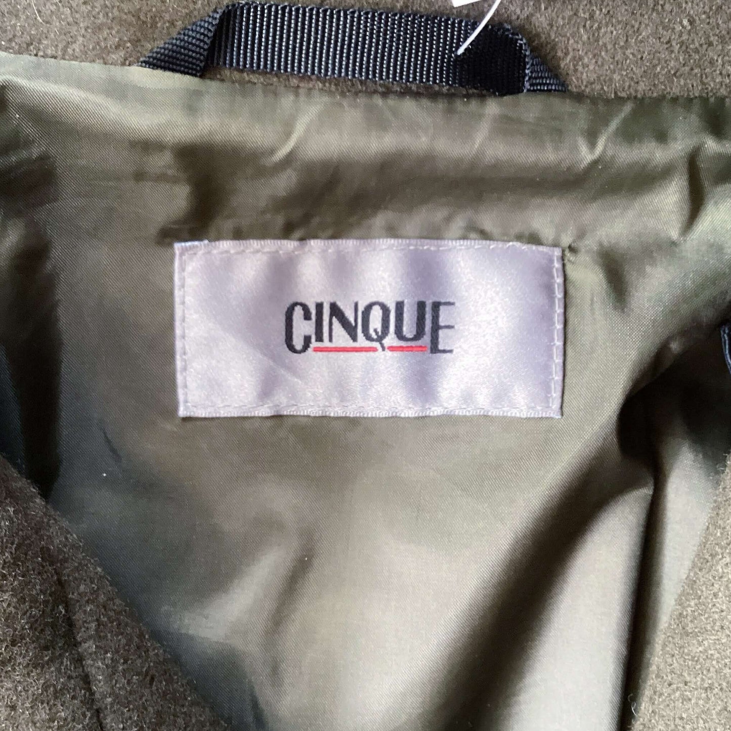 label view of the jacket, deep brown/olive hue, zip and large stud closing mechanism.