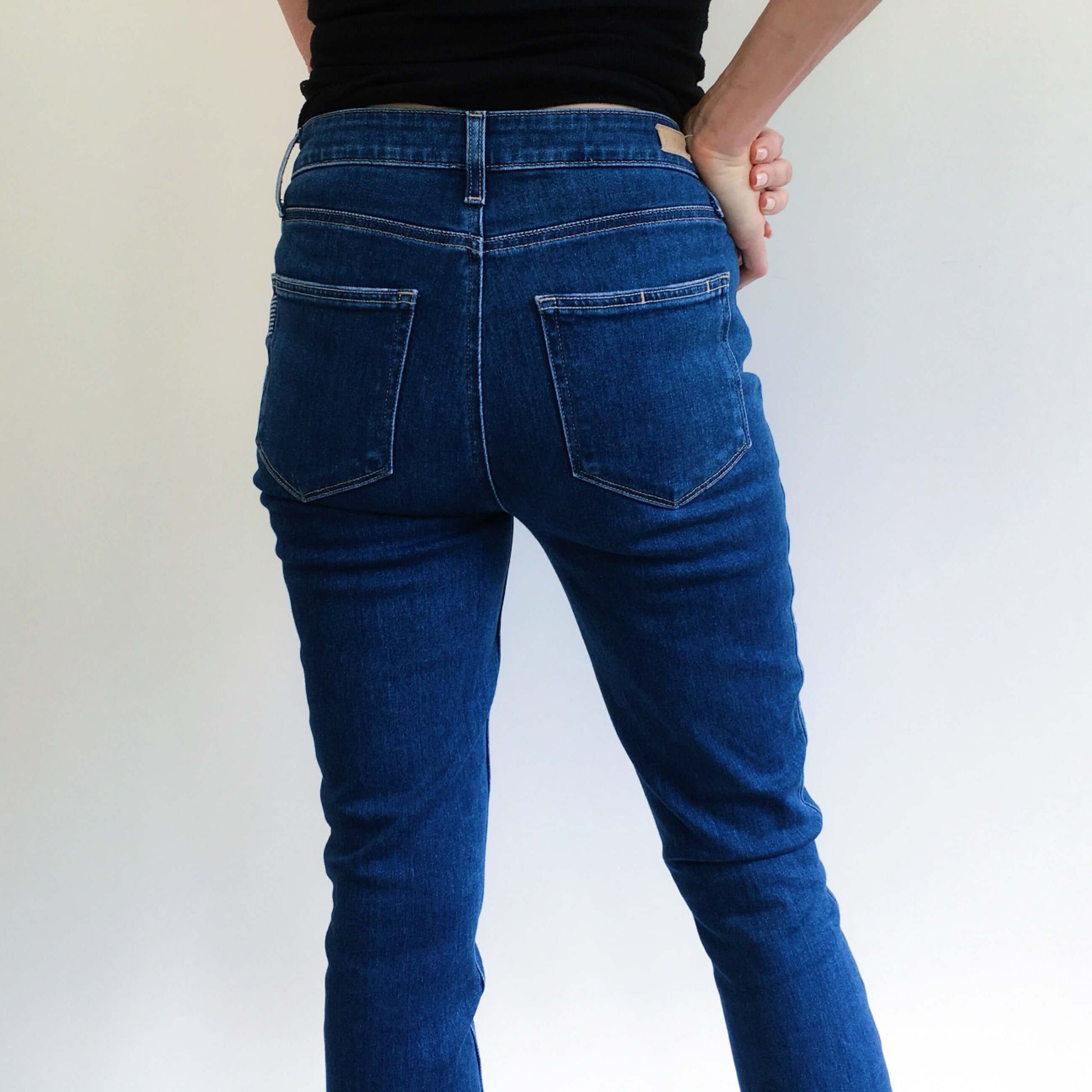 Back detail view uniform color navy blue jeans waist to calf.