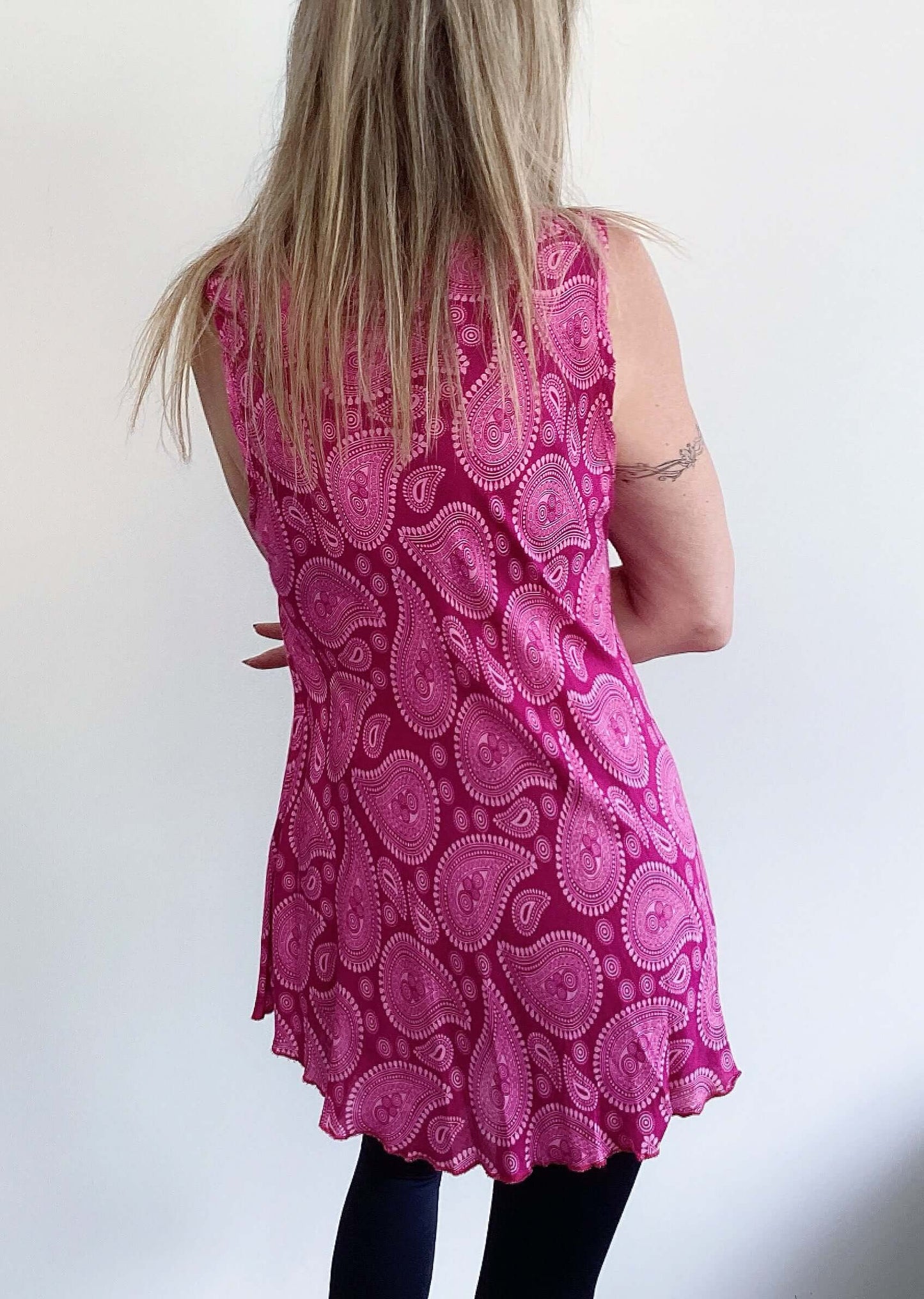 Back view of button up tunic top, cut wide around the hip, sleeveless v neck.