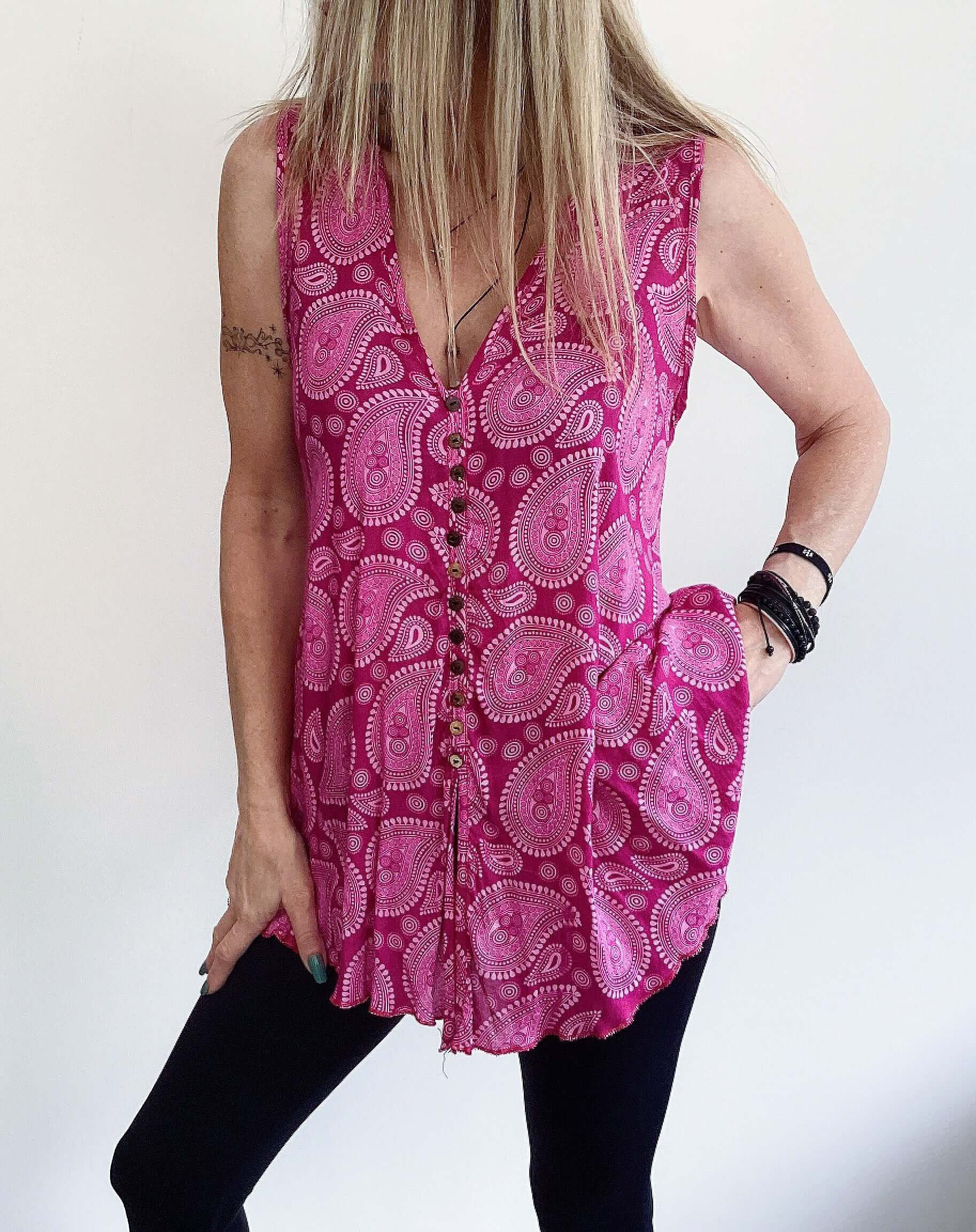 Front view of button up tunic top, cut wide around the hip, sleeveless v neck, small black buttons.