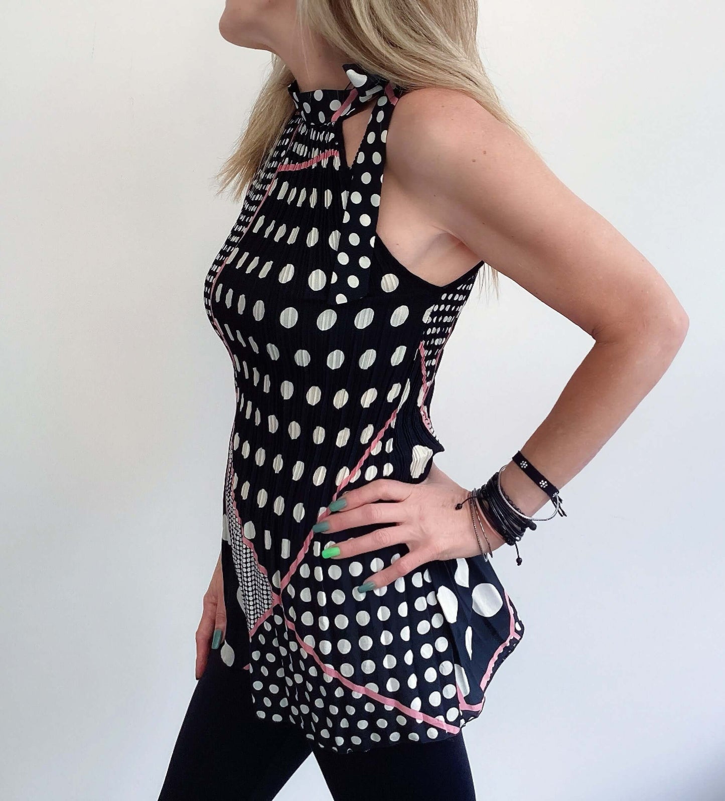 Side view black and white polka dot top, pink piping accents, tied at the neck with matching fabric, length upper thigh.