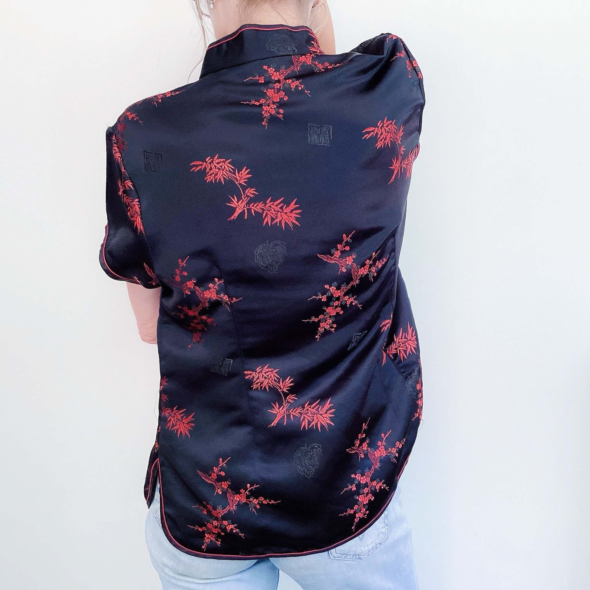 Back view of black tunic, hip length, with red printed organics, short sleeve.