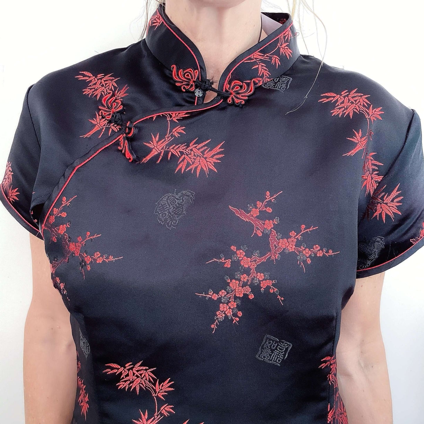 Detail view of black tunic, chinese collar, with red printed organics, short sleeve.