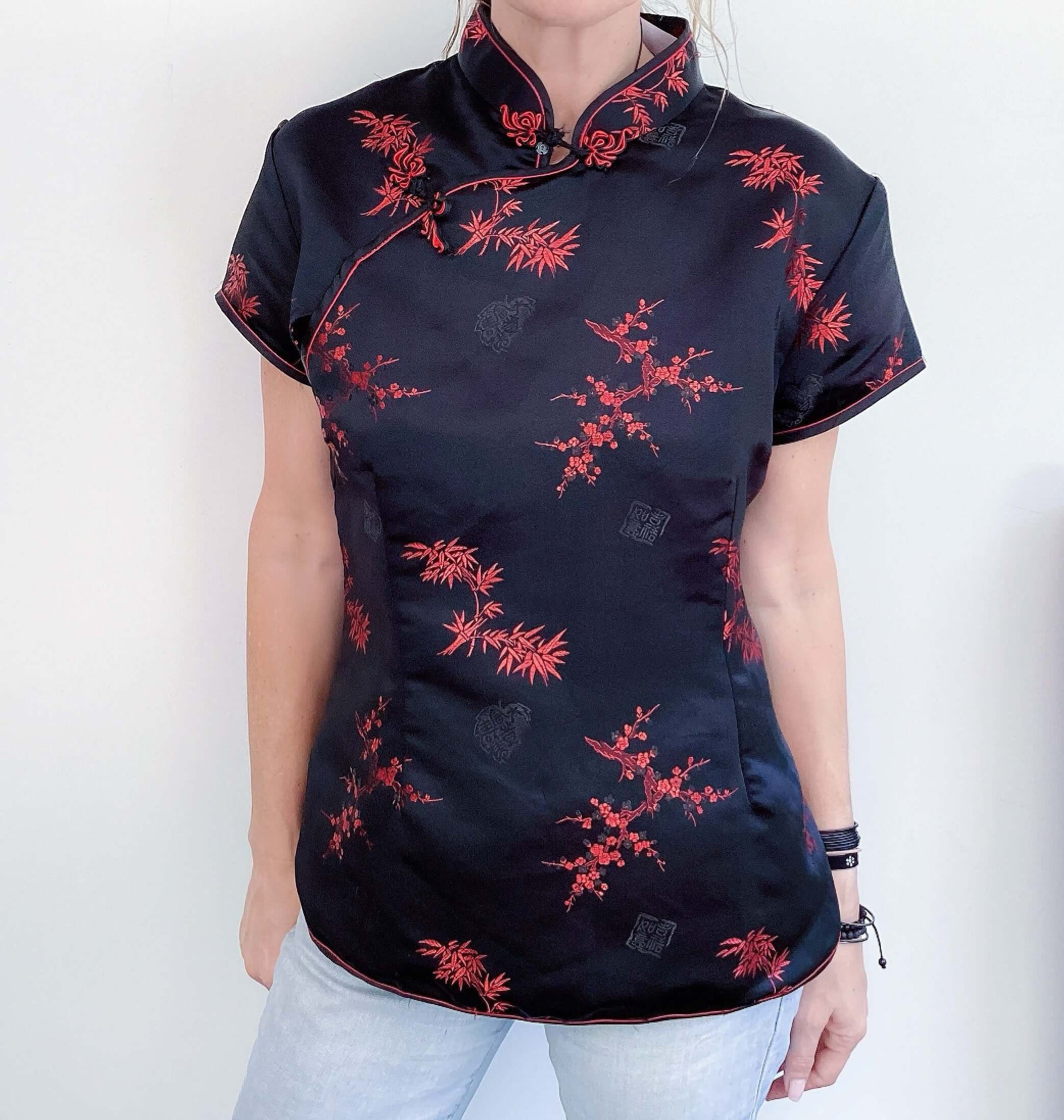 Front view of black tunic, hip length, with red printed organics, short sleeve.