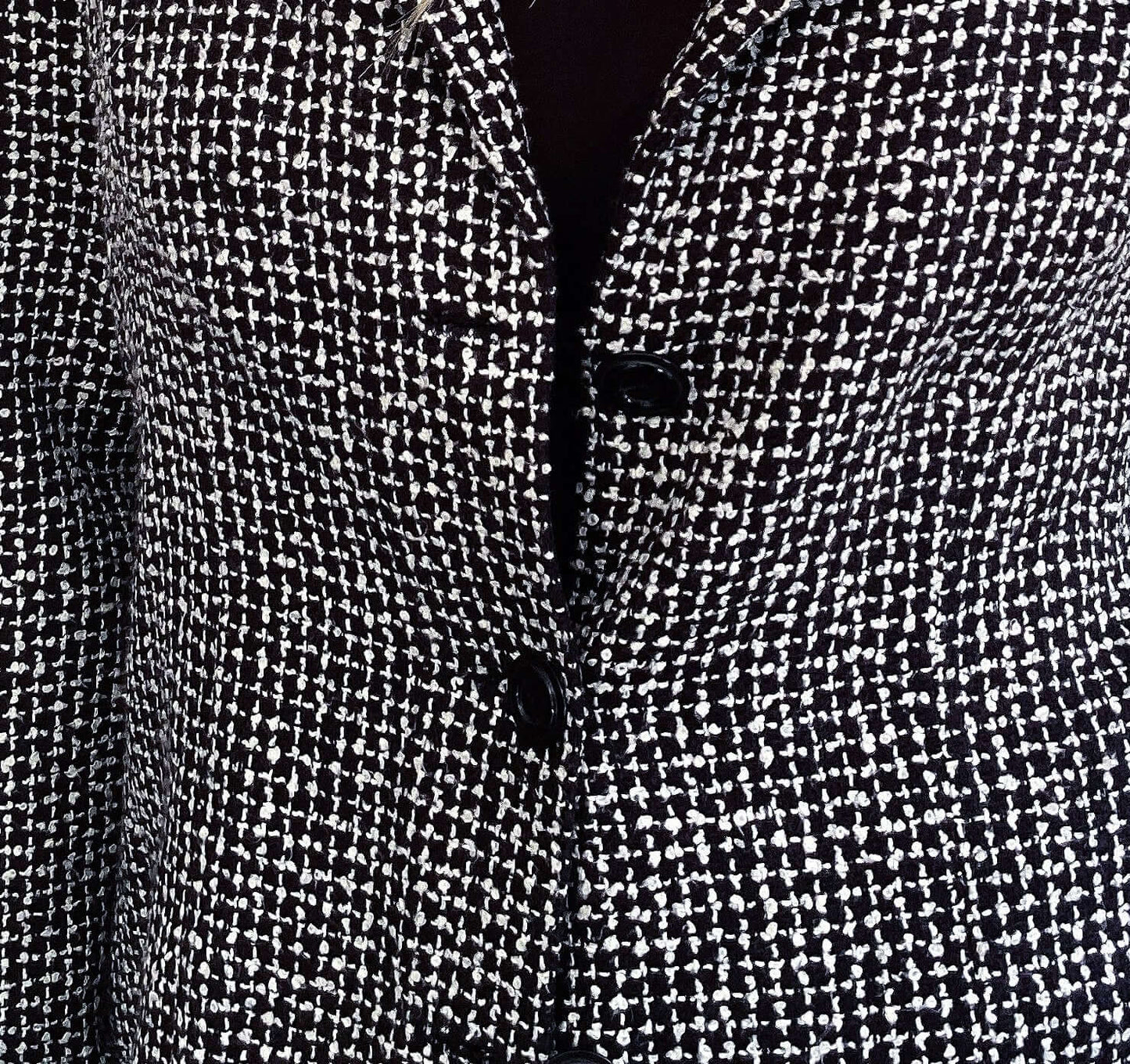 Detail view of black and white soft tweed blazer with 3 black buttons.