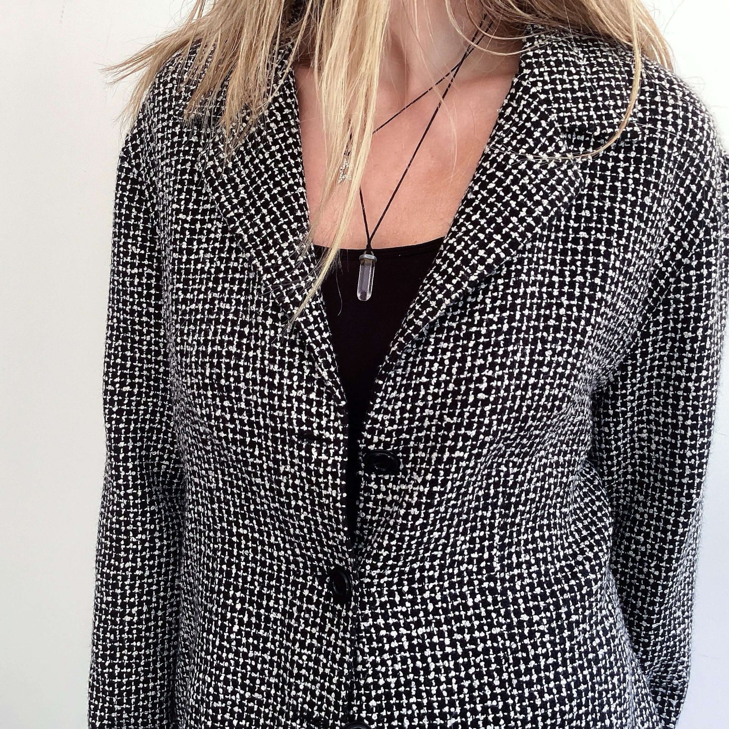 Side view of black and white soft tweed blazer with 3 black buttons.