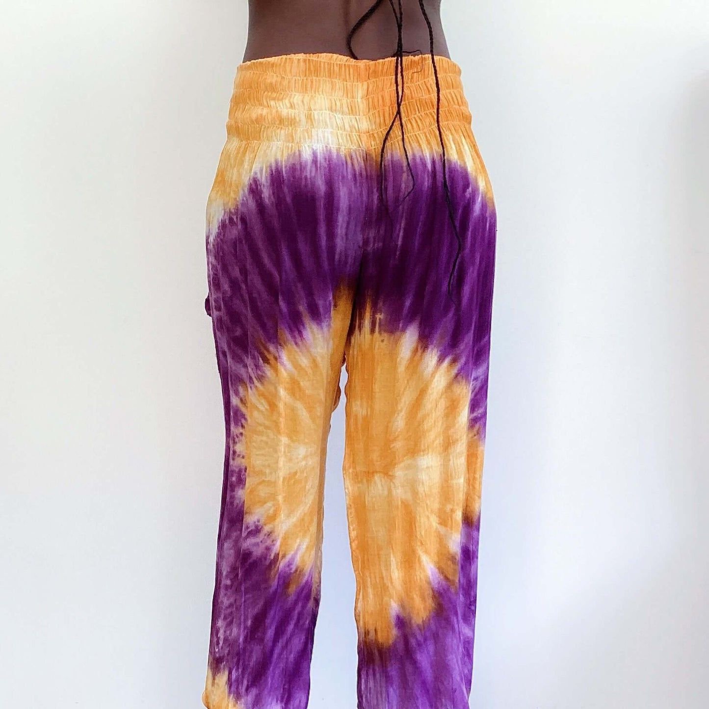 Back view of tie dyed orange and purple harem pants, ruched waistband, elasticated ankle.