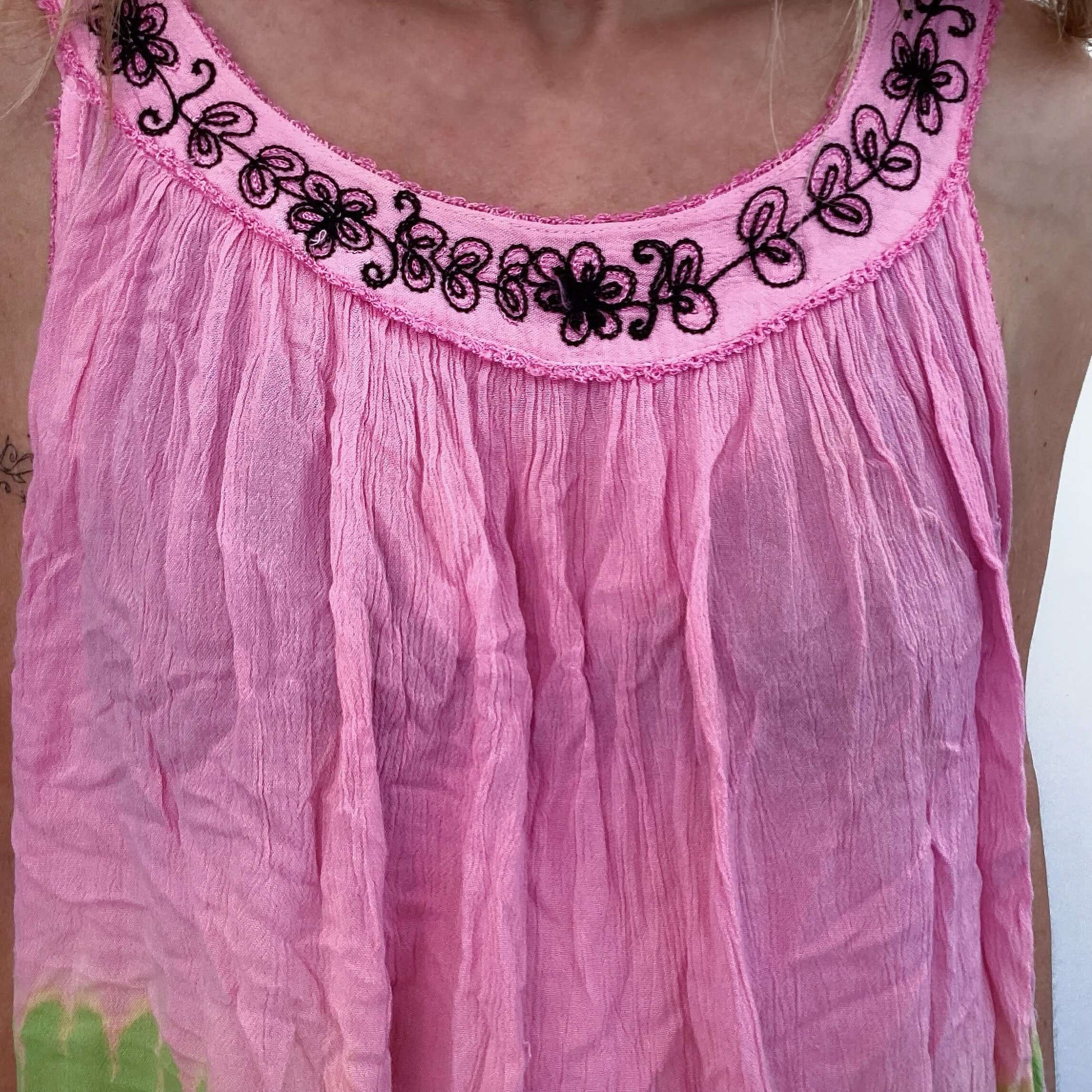 Detail view of tie-dyed pink top, with embroidered edges on the circular open arm straps.