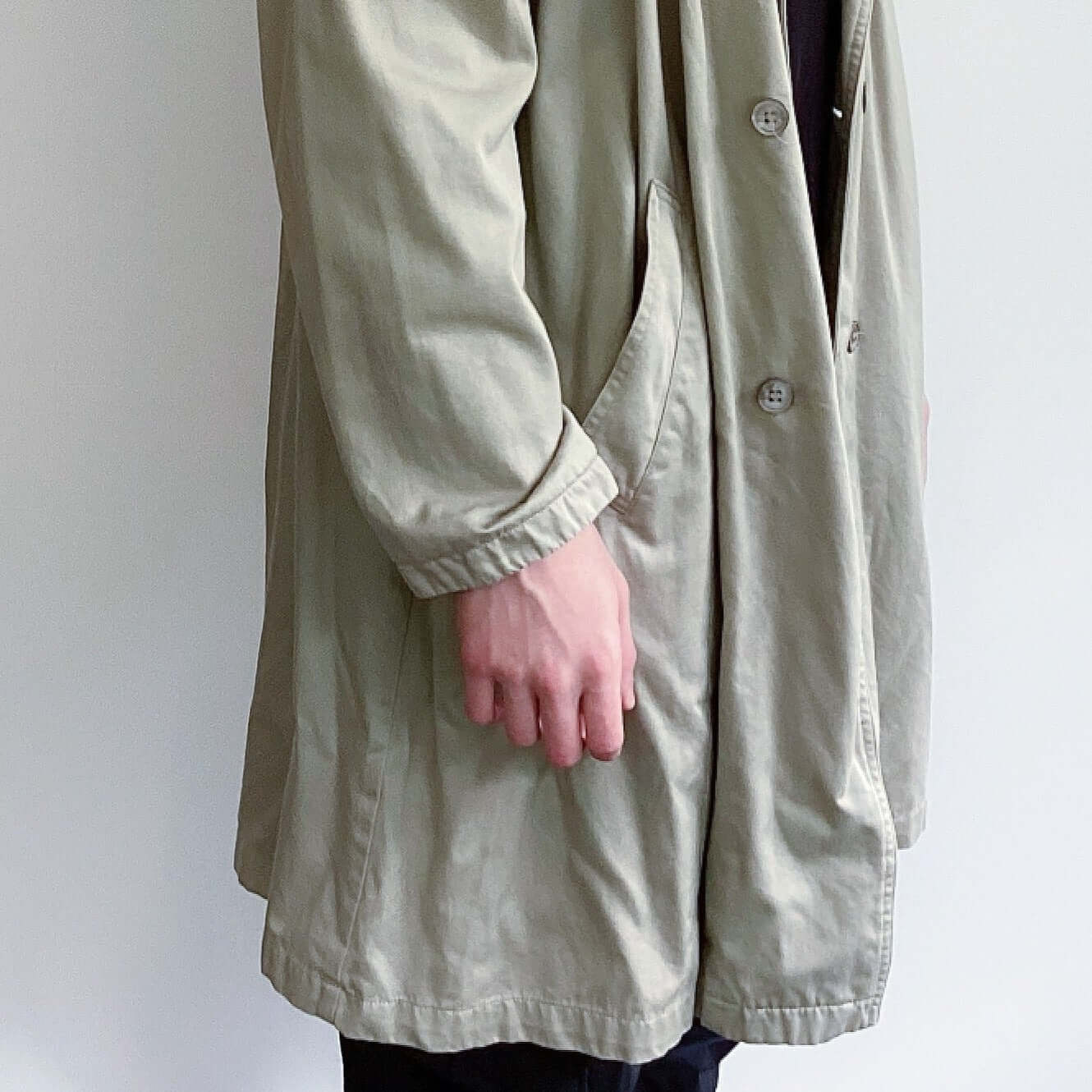 Beige double-breasted knee length jacket, side view.