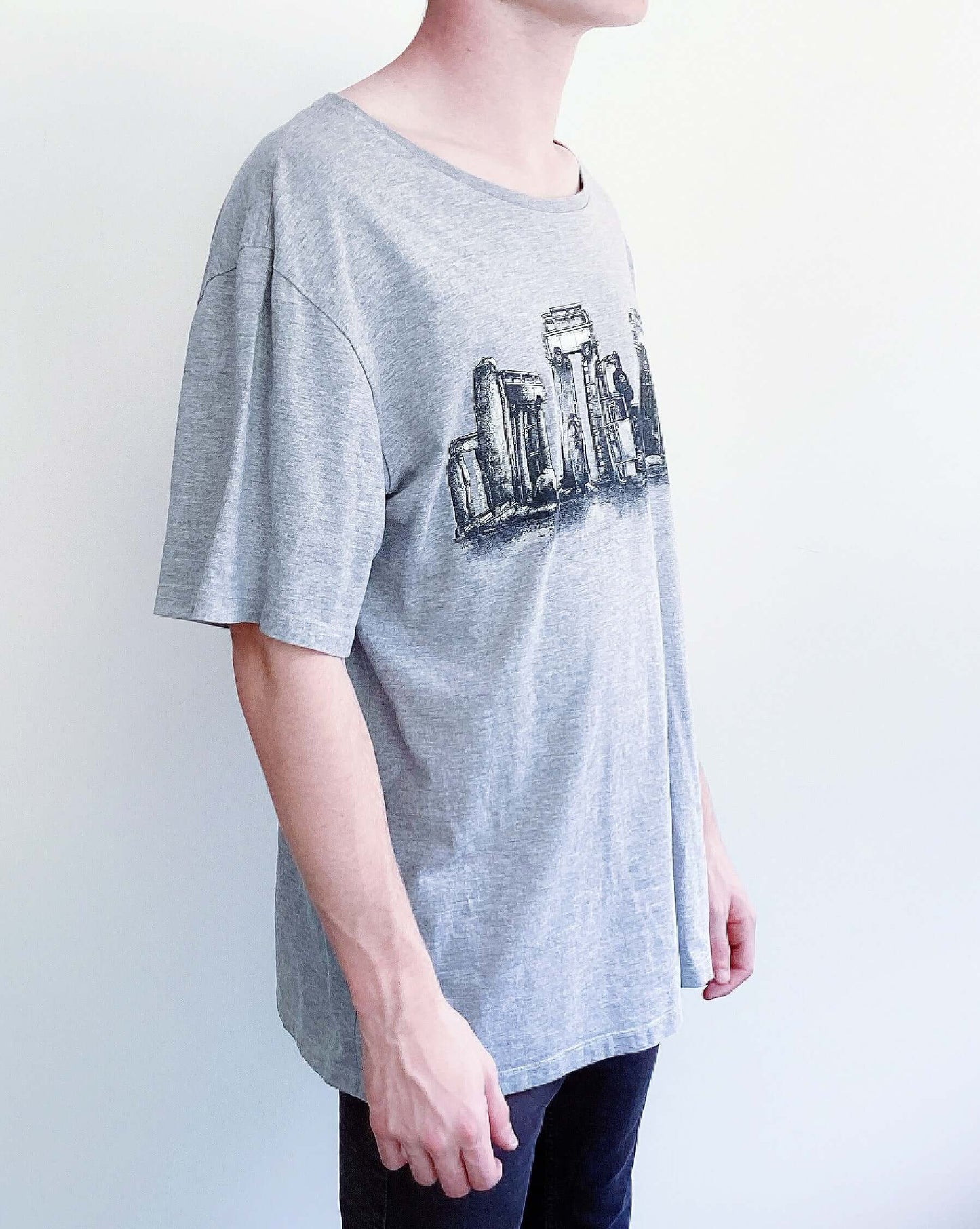 Side view of grey tshirt with vw buses positioned into stonehenge shapes, printed across the chest in black and white.