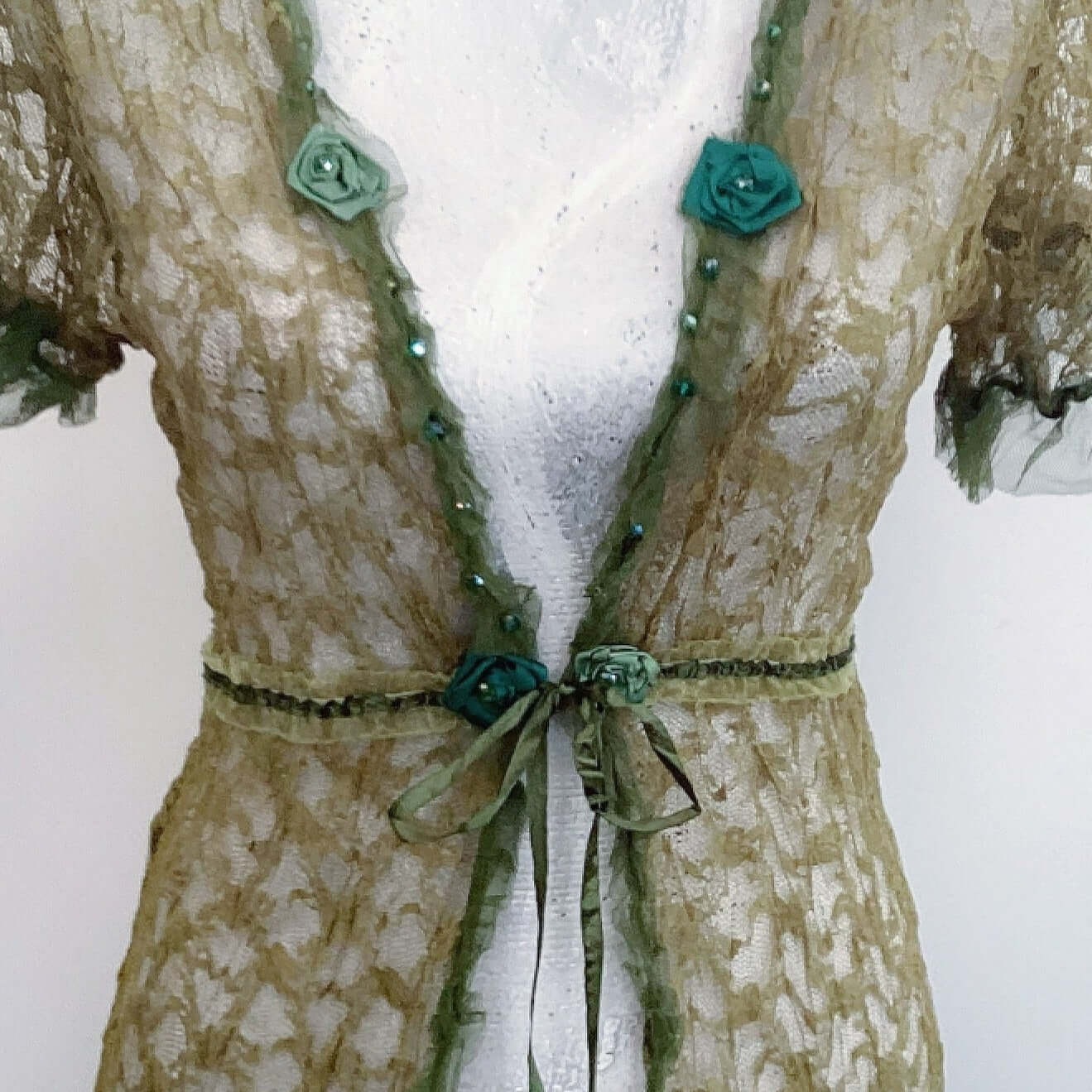 Front detail view of tie jacket, olive lace all over, showing beadwork and roses.