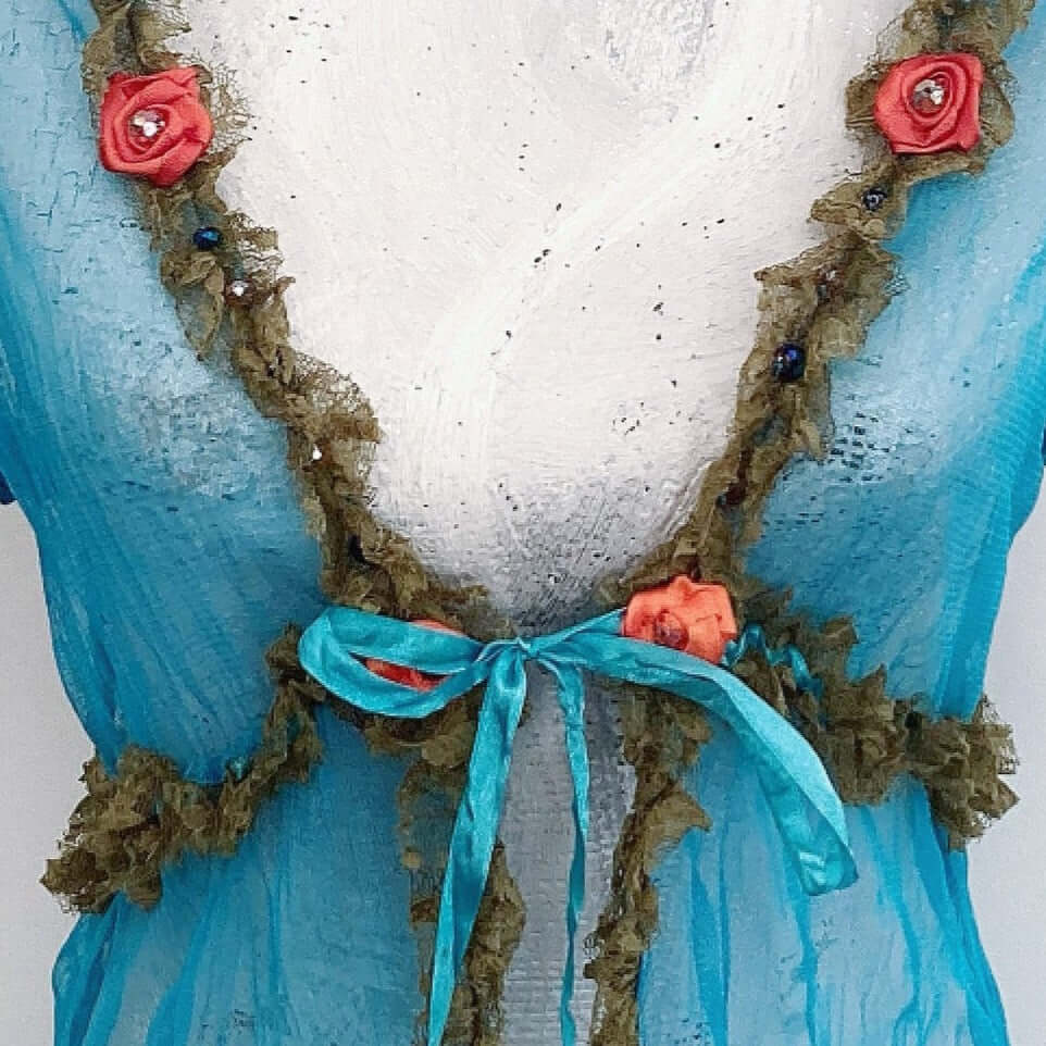 Close-up of front turquoise satin ribbon tie, narrow olive lace ruched under bust, up to shoulder. Beads and 4 orange roses.