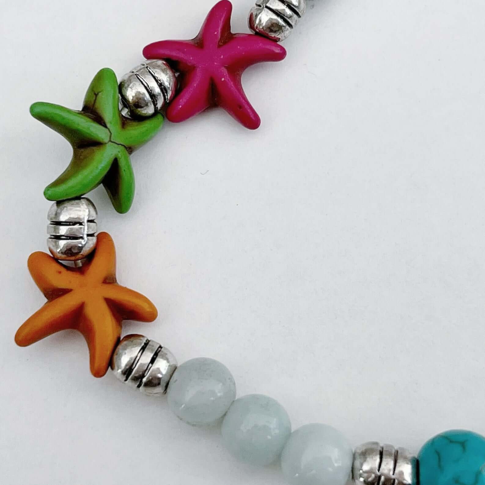 Detail view of the orange, green and pink starfish, with Blue Lace Agate beads on either side.