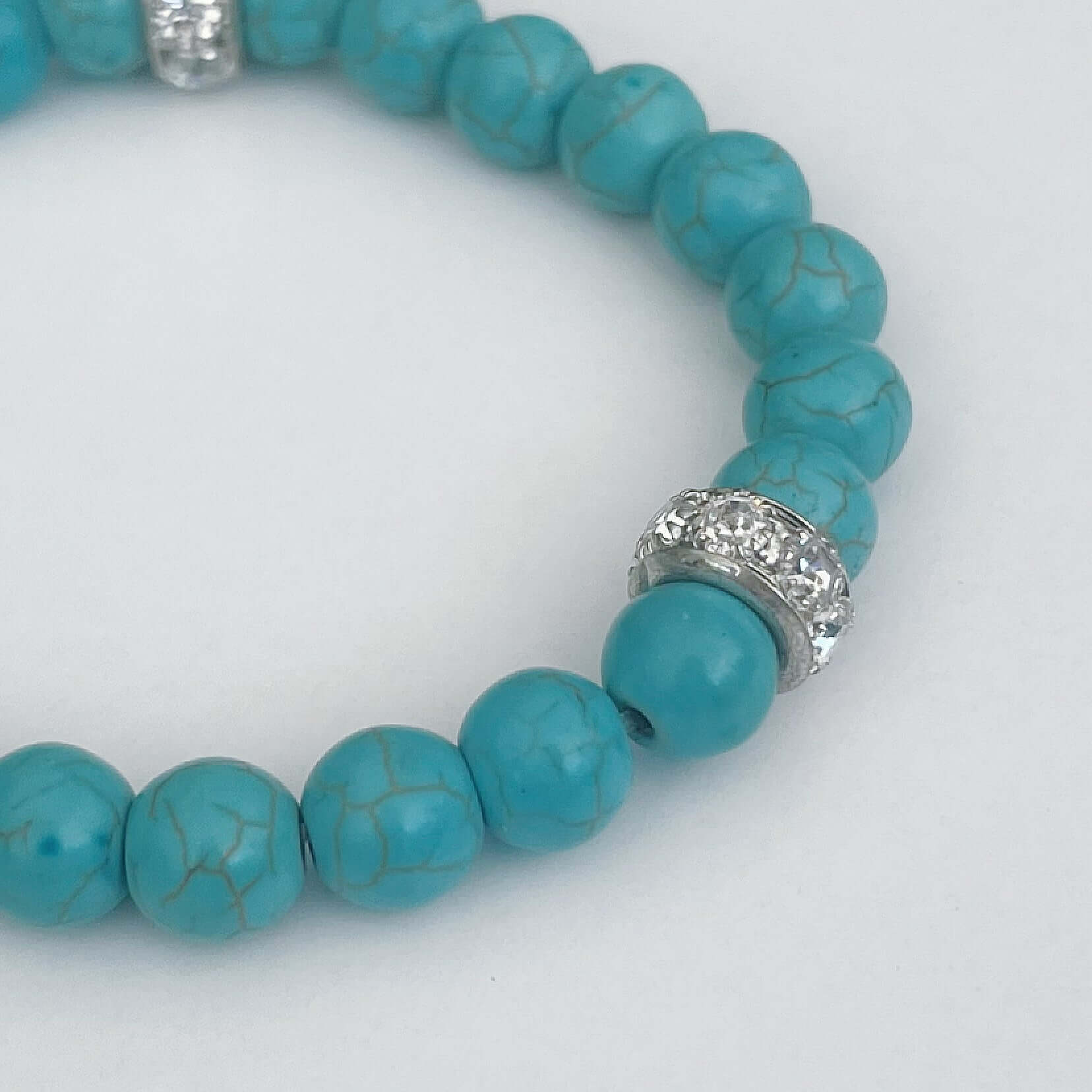 Detail view of bracelet, showing the individual turquoise beads, with pale black striations and diamanté dividers.