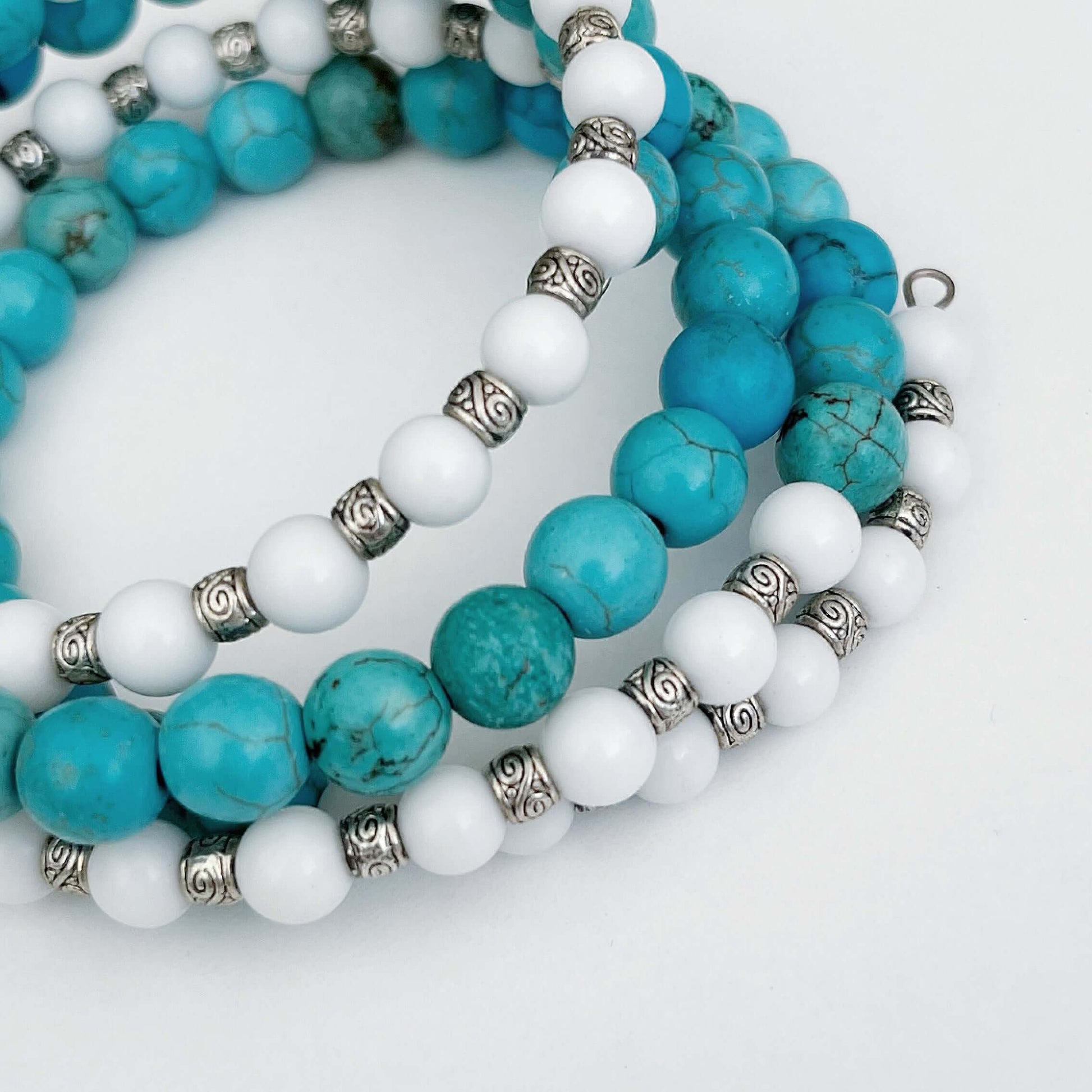 Detail view of bracelet, mixture of Blue Howlite in sections, alternating with white glass and silver finish bead sections.